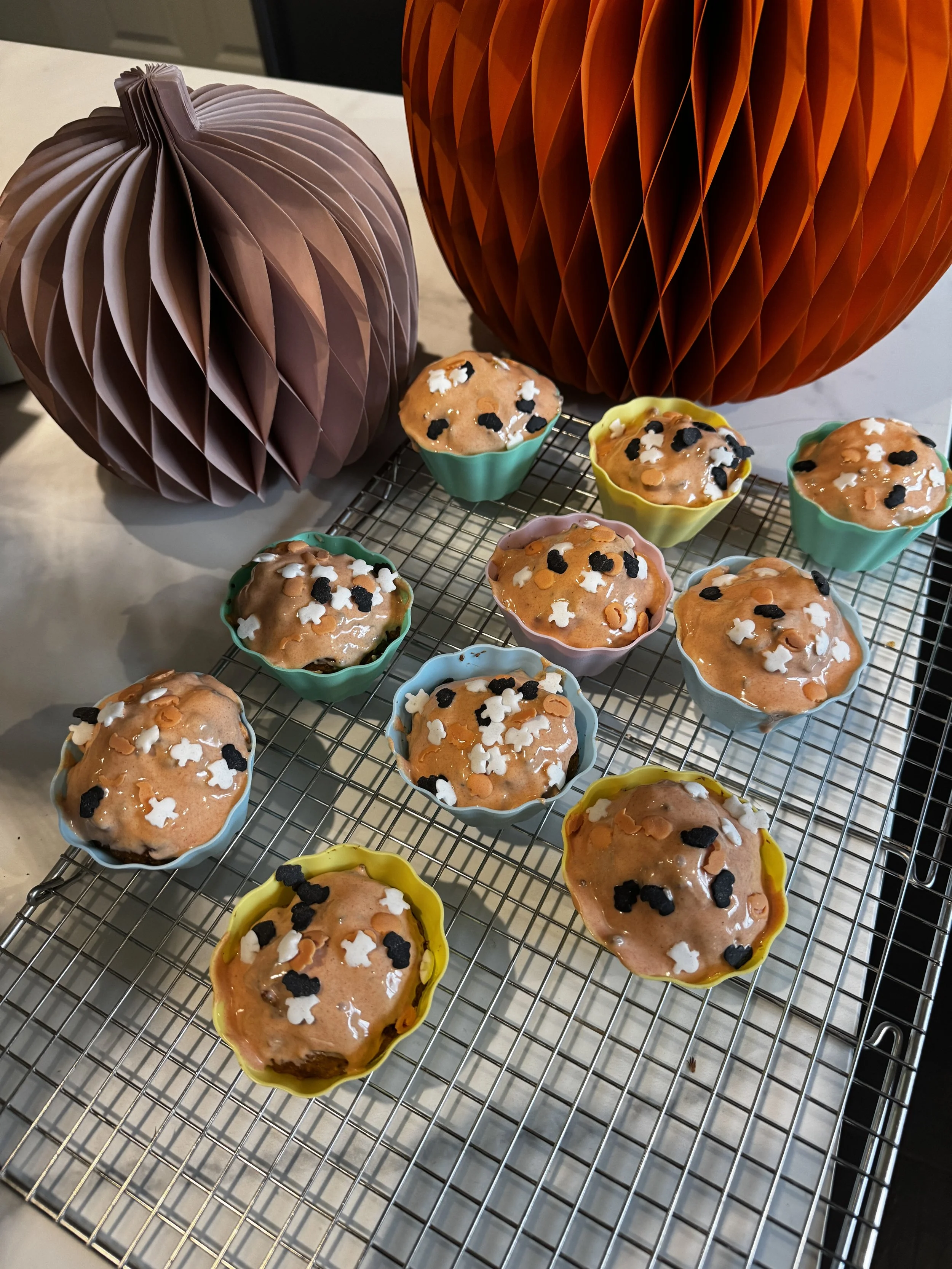Kürbis Karotten Muffins für Halloween im Kindergarten auf dem Auskühlgitter vor Papierkürbisen