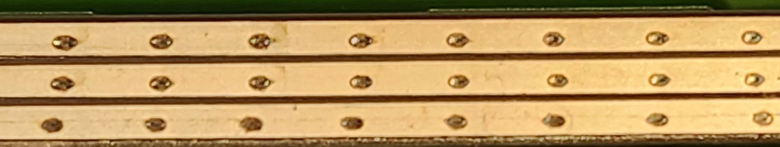 Close-up of a light-colored wooden surface with evenly spaced metallic screws.