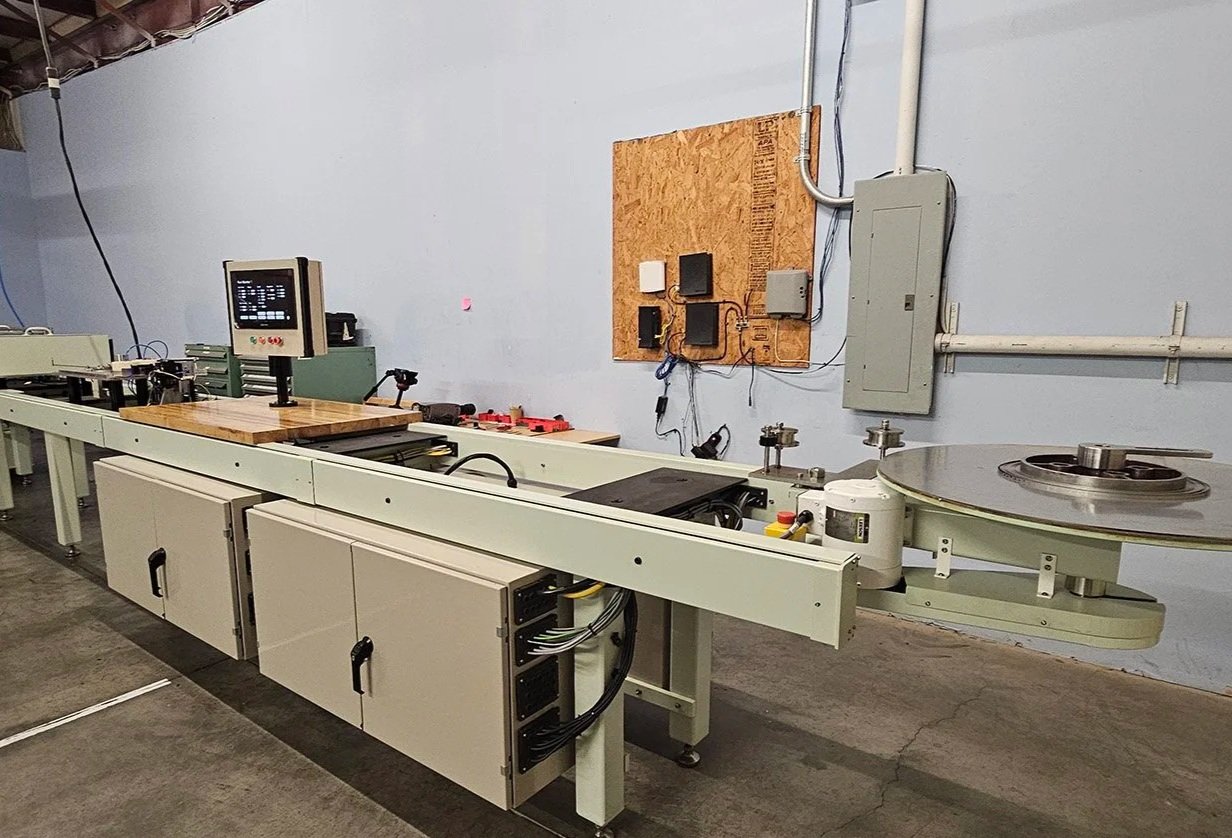 Industrial machine used for manufacturing or processing, with control panel and rotating component on the right, located in a workshop with electrical panels and wall-mounted equipment.