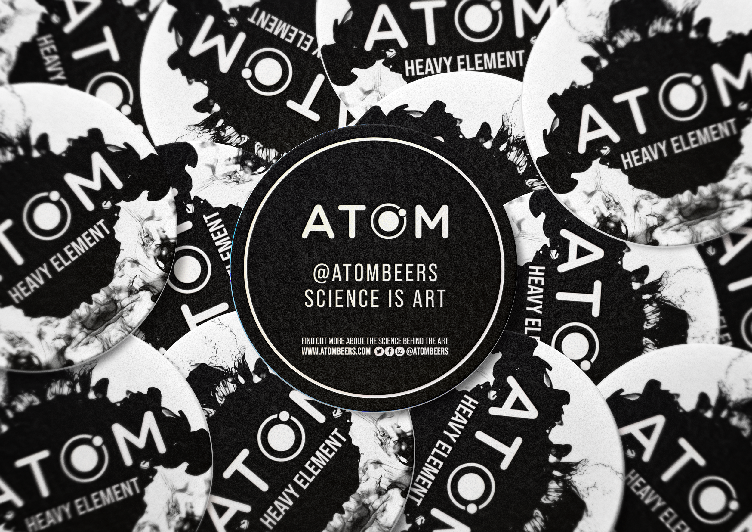 A collection of black and white circular stickers with the word 'ATOMIC' and related science-themed text and graphics. Some stickers have the phrase '@ATOMBEERS SCIENCE IS ART' and social media icons.