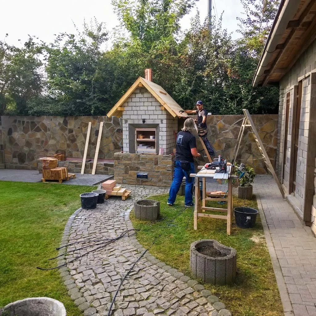 das team von kaminstudio pasing baut in einem garten einen pizzaofen auf