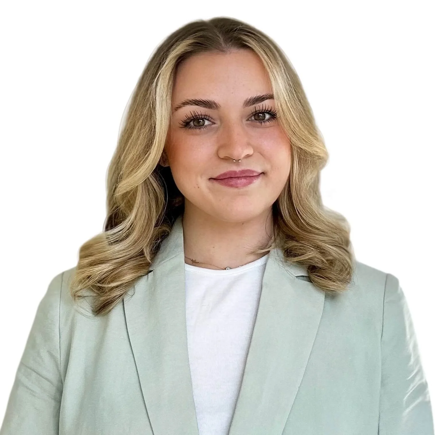 A woman in a green blazer paired with a white shirt, with blonde hair and brown eyes smiling into the camera