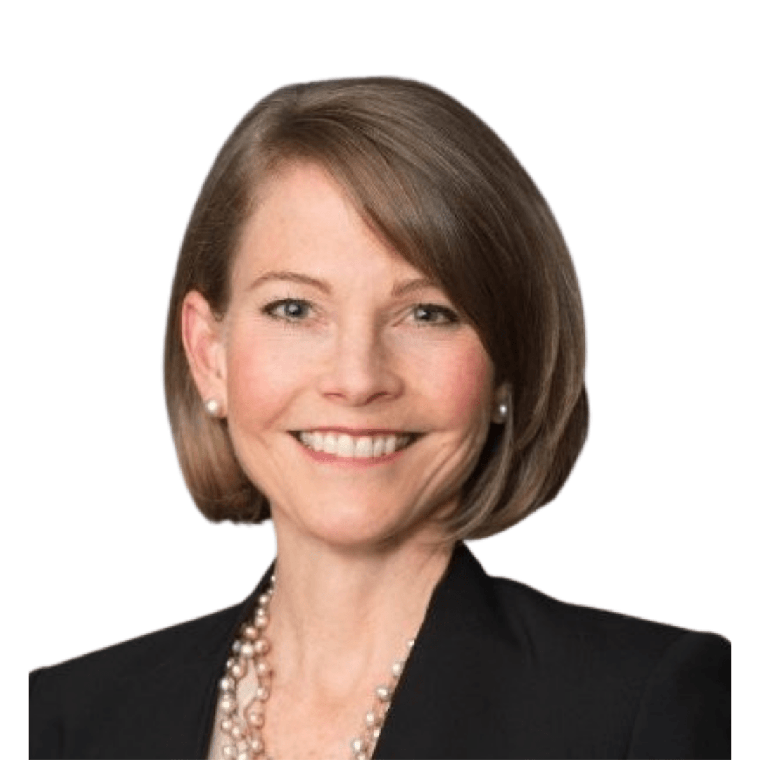 Professional headshot of a smiling woman with a short brown bob, wearing a black blazer and layered pearl necklace against a white background.