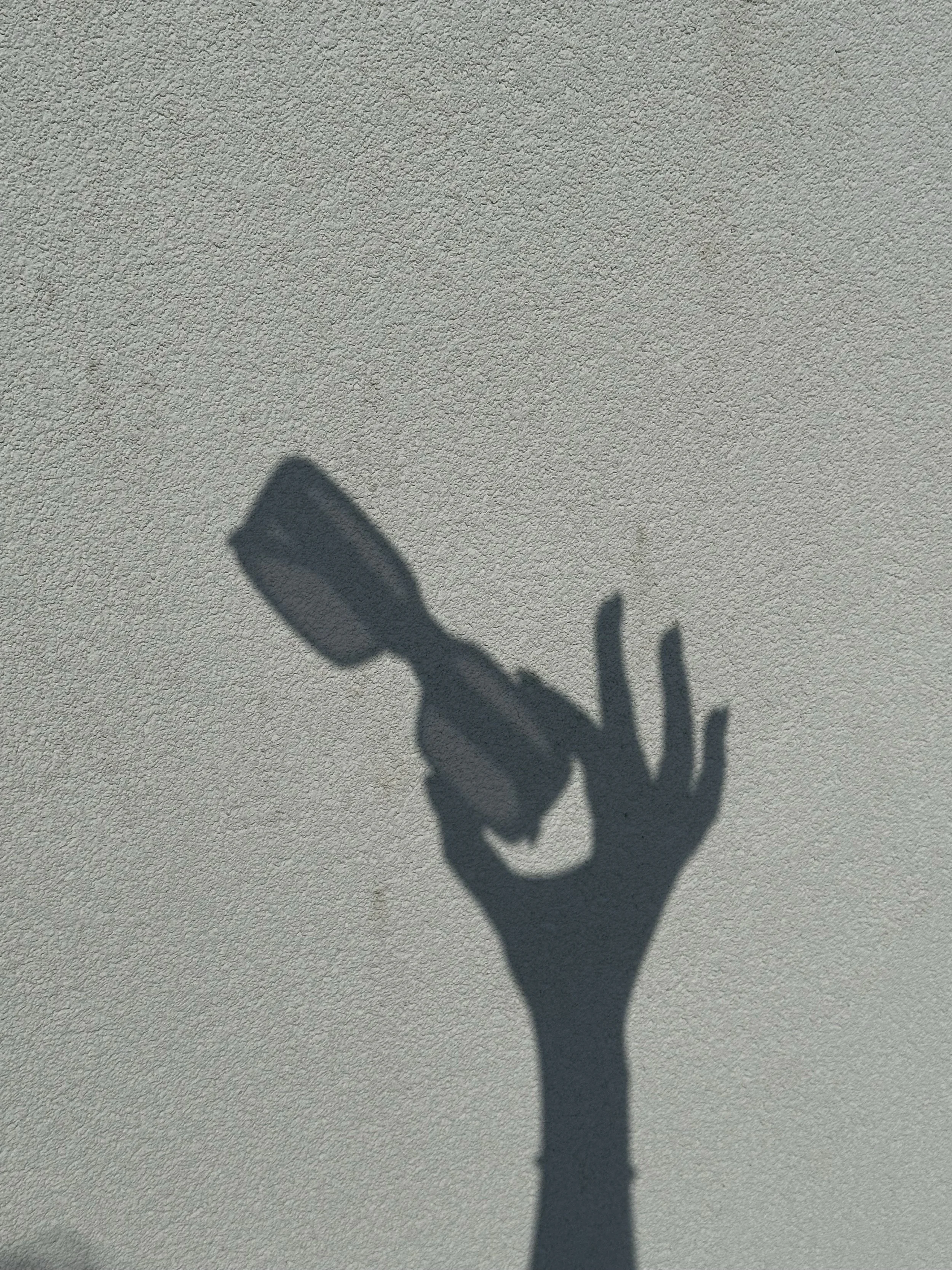 Schaduw van een hand met een lichtbron op een witte muur.