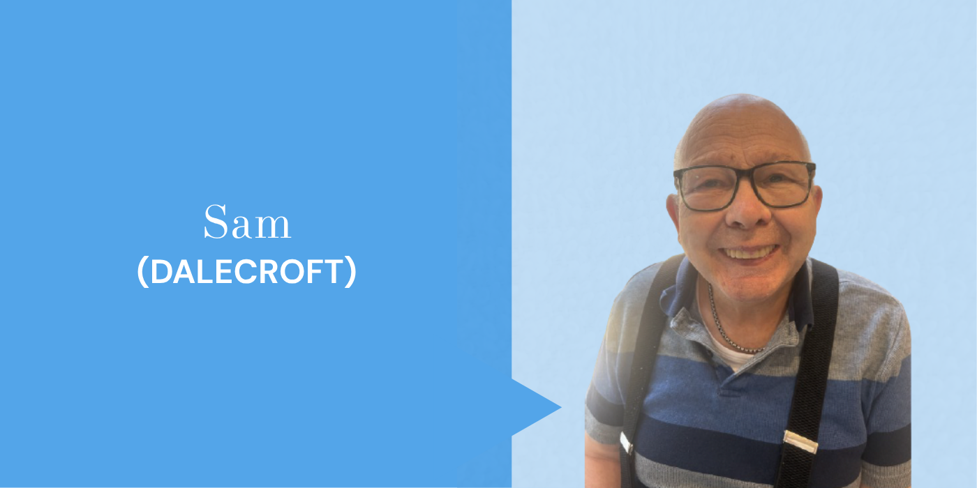 A smiling elderly man with glasses, a striped polo shirt, and a backpack, standing against a light blue background.