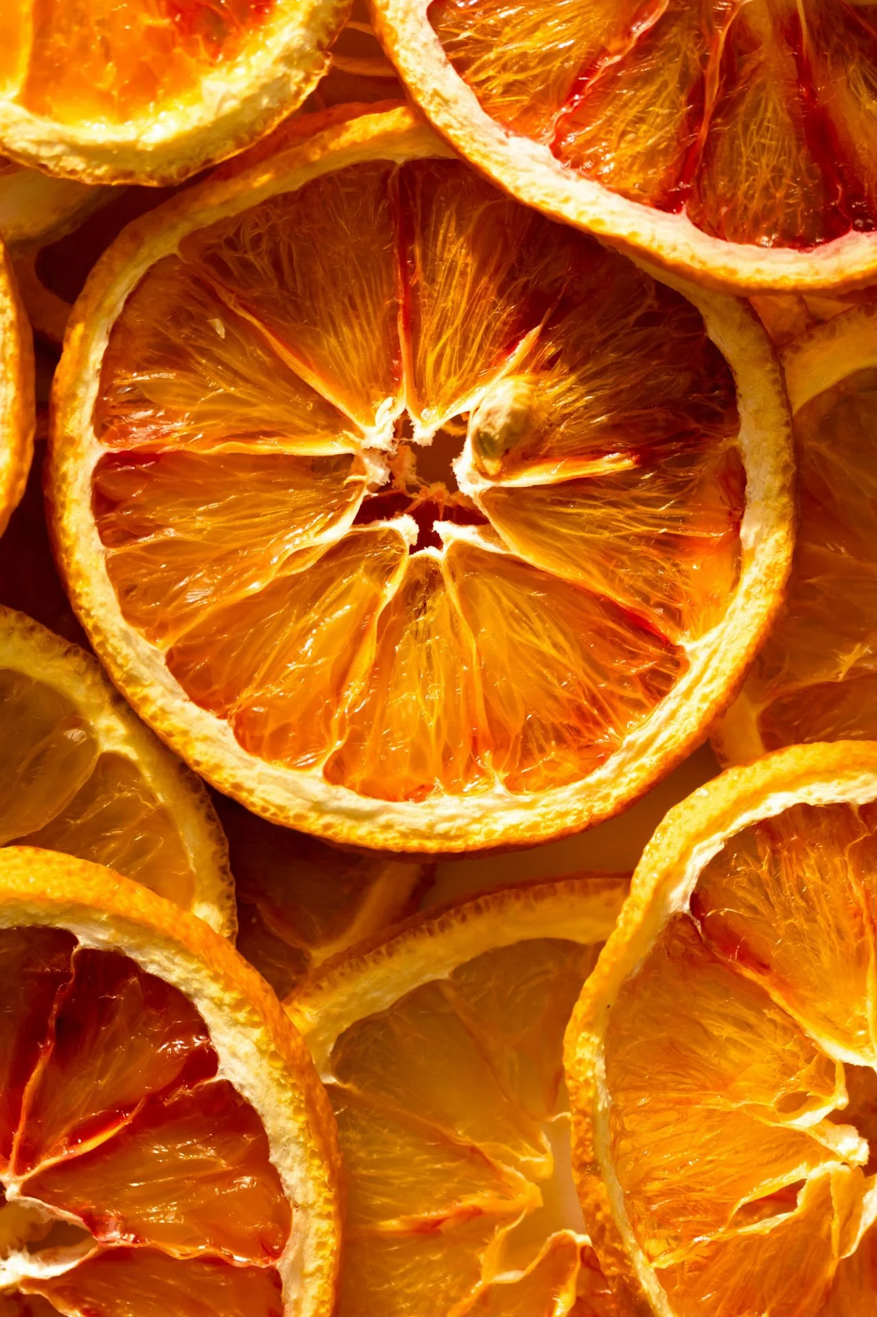 Close-up of sliced dried oranges with vibrant orange color and visible interior patterns.