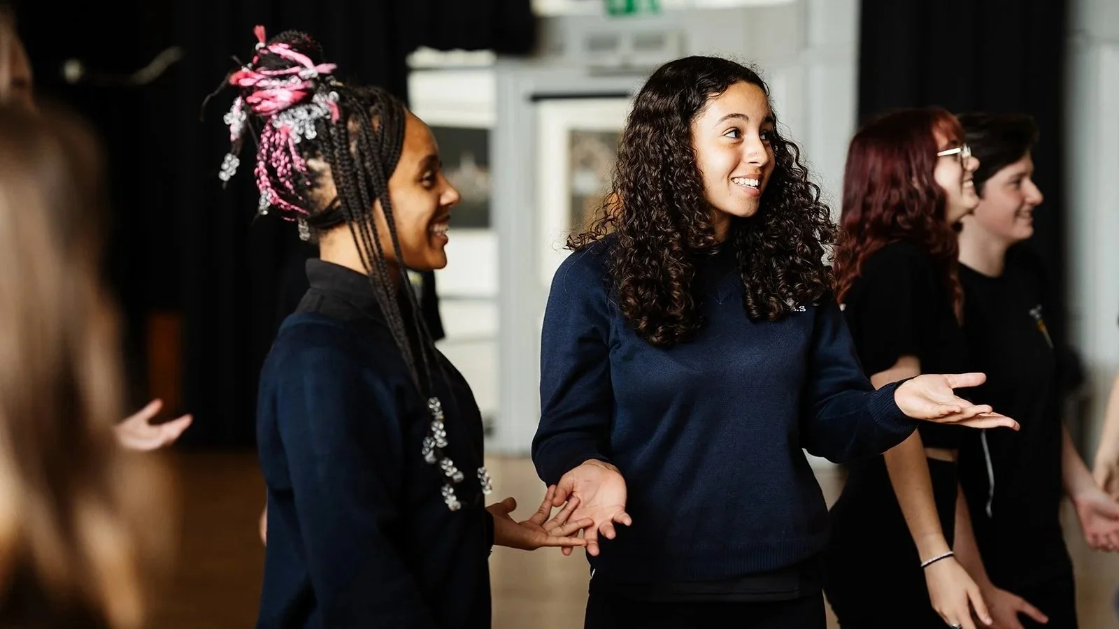 Two students smile, looking off camera as they take part in a schools workshop
