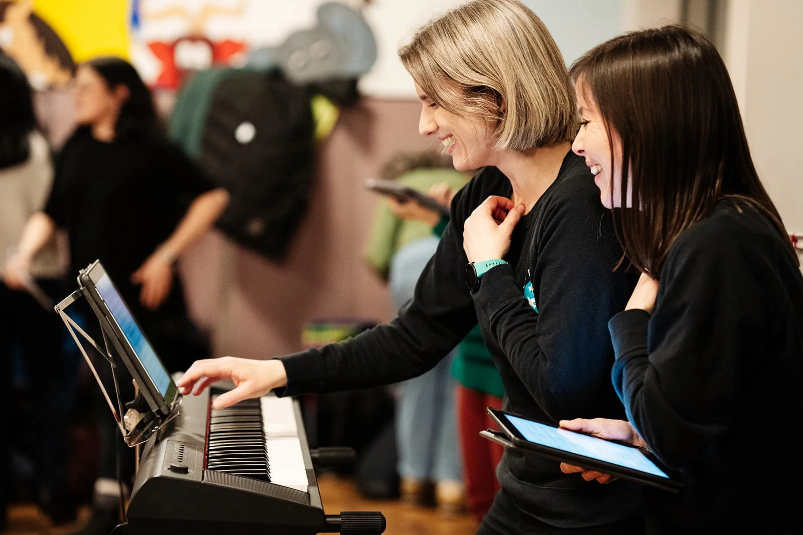 Anna Shields & Emily Garsin laugh as they lead a session around a keyboard