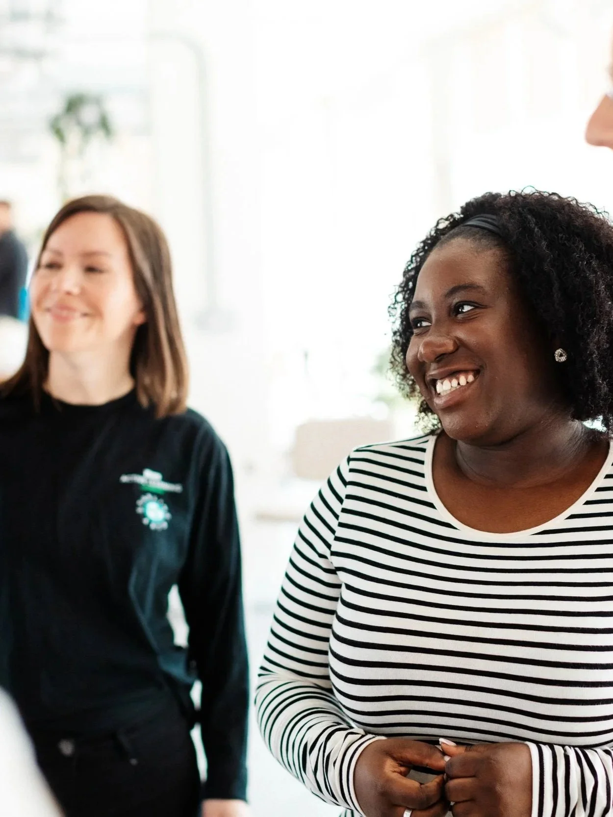 An Official Wicked Workshop participant smiles, wearing a stripey top, with Emily Garsin of Starling Arts in the background