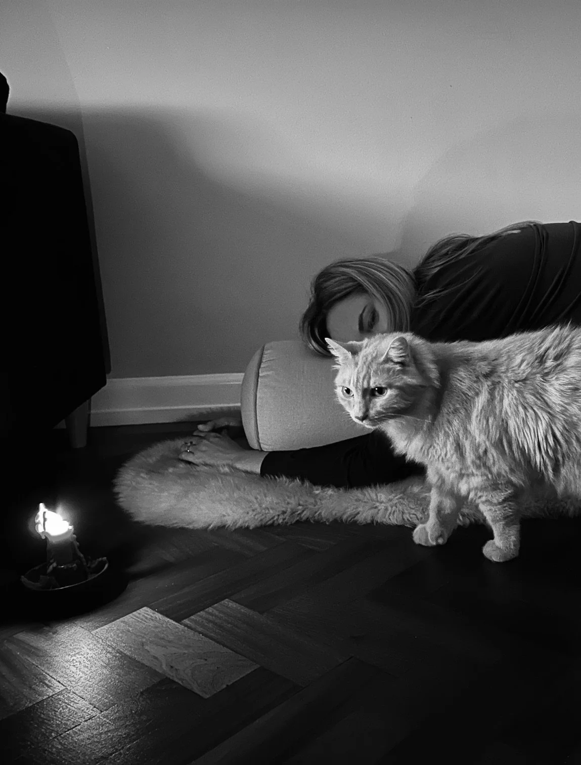 Woman resting on a yoga bolster with a cat nearby, enjoying a cozy moment of relaxation and mindfulness.