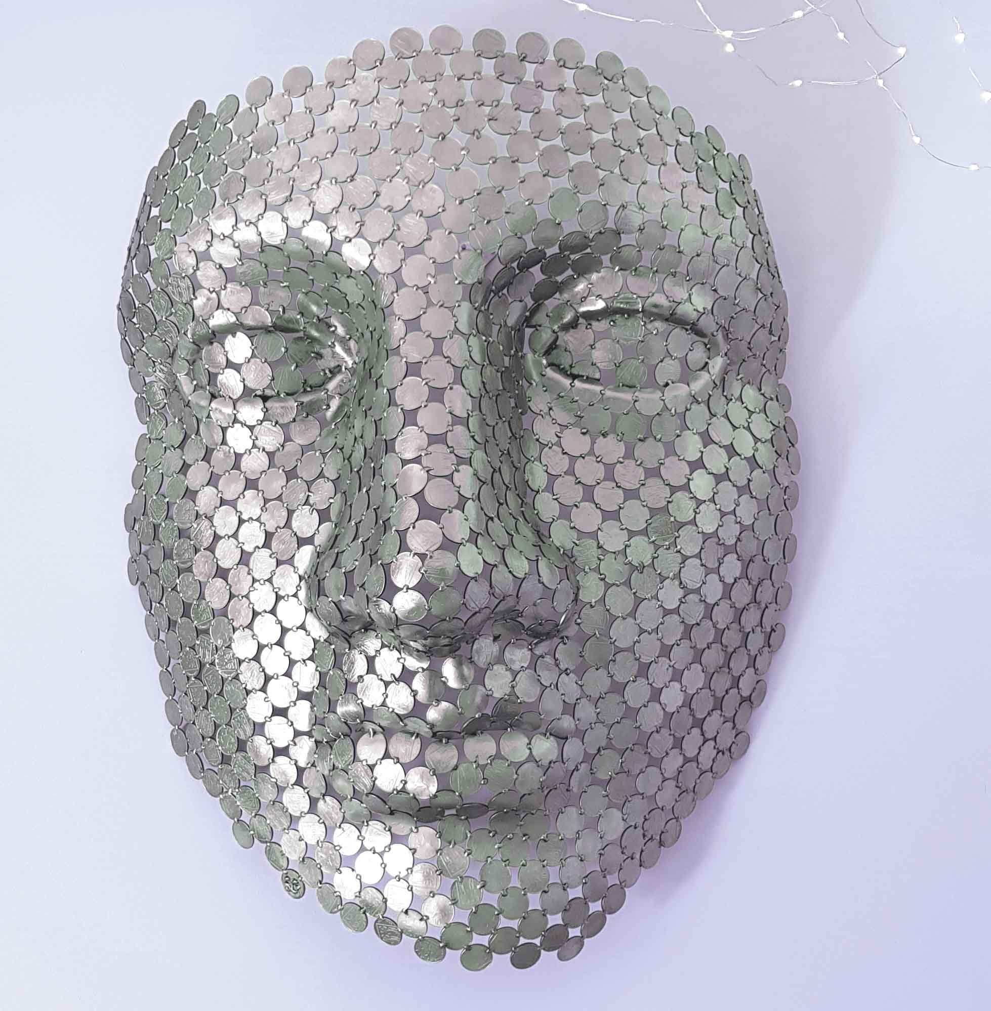 A magnificent face sculpture by Shaun Gagg crafted from 10p coins. This intricate piece captures striking facial features and texture, designed to hang elegantly on the wall,
