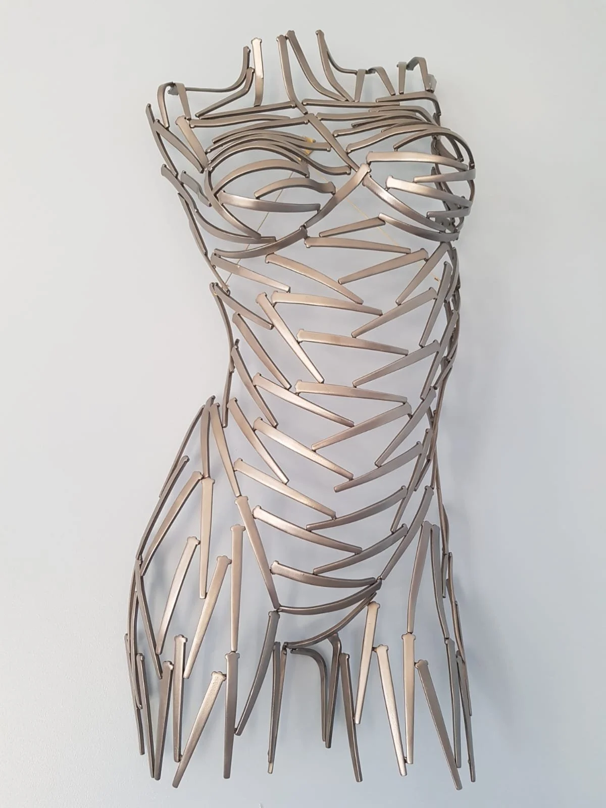 A torso sculpted from nails—sharp, textured, and raw. Suspended or grounded, it plays with light and shadow, turning metal into movement.