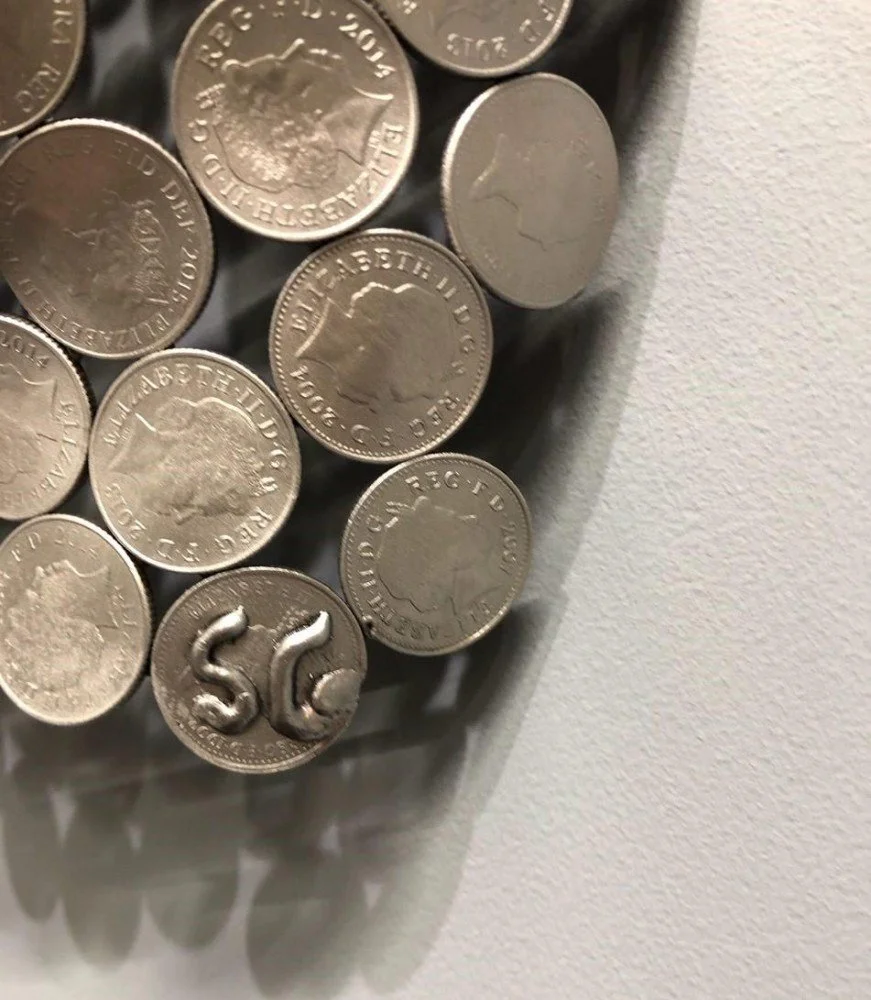 A 10P Torso Rear" by Shaun Gagg, a life-size sculpture crafted from 10p coins. It can be displayed on a base or hung on a wall, offering versatility in showcasing the detailed artistry of the piece.