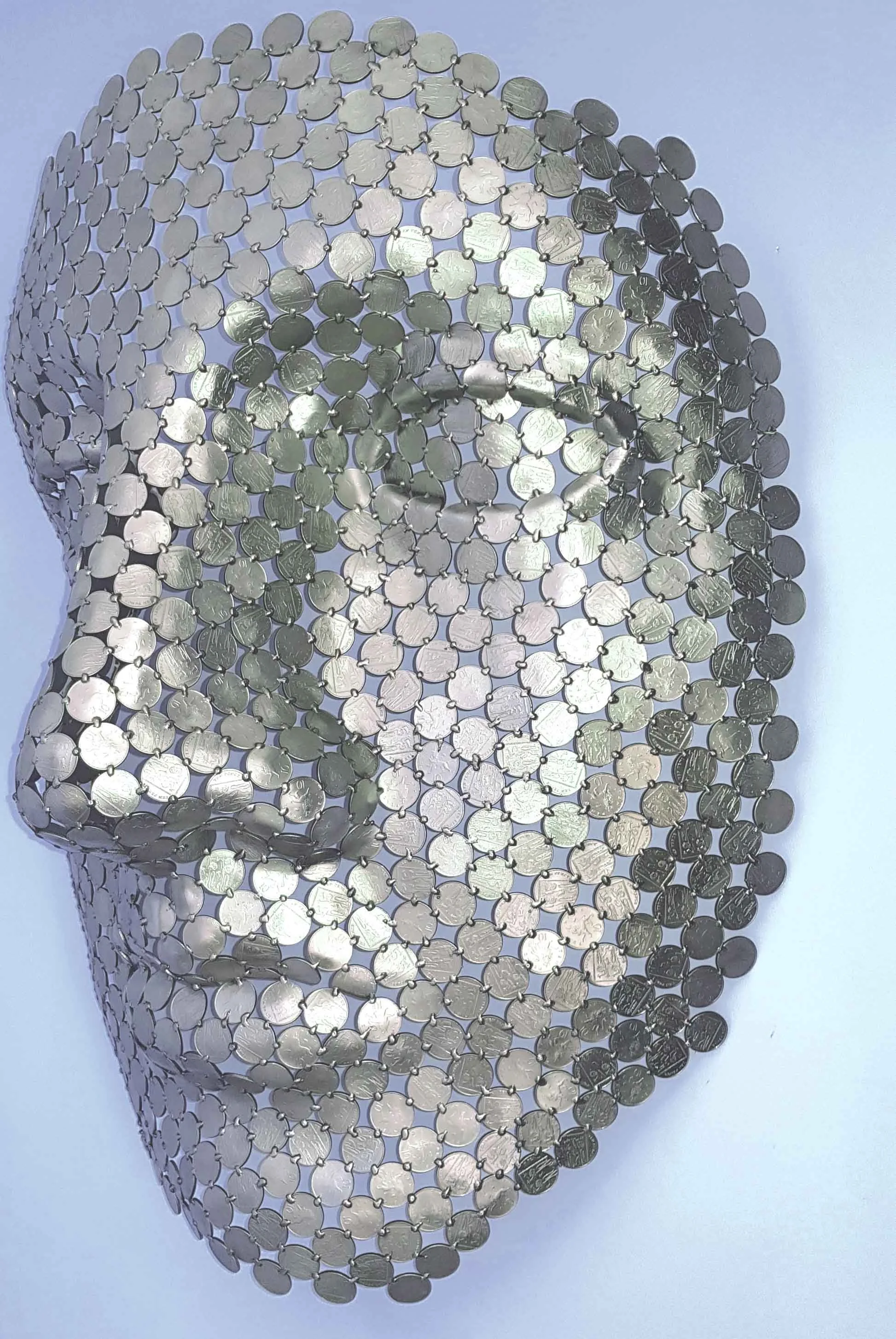 A magnificent face sculpture by Shaun Gagg crafted from 10p coins. This intricate piece captures striking facial features and texture, designed to hang elegantly on the wall,
