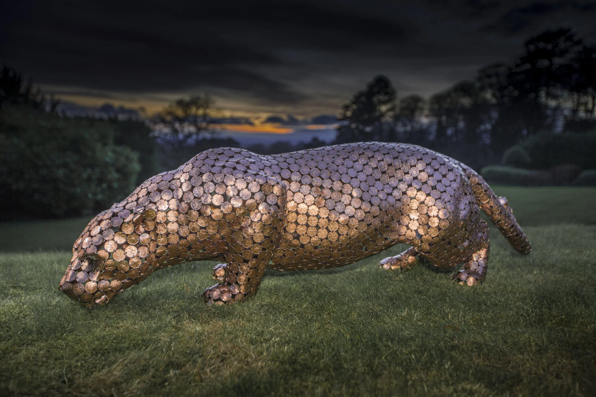 Life-size jaguar sculpture by Shaun Gagg, made from welded 2p coins. The shiny coins reflect light, highlighting the jaguar's powerful form and texture