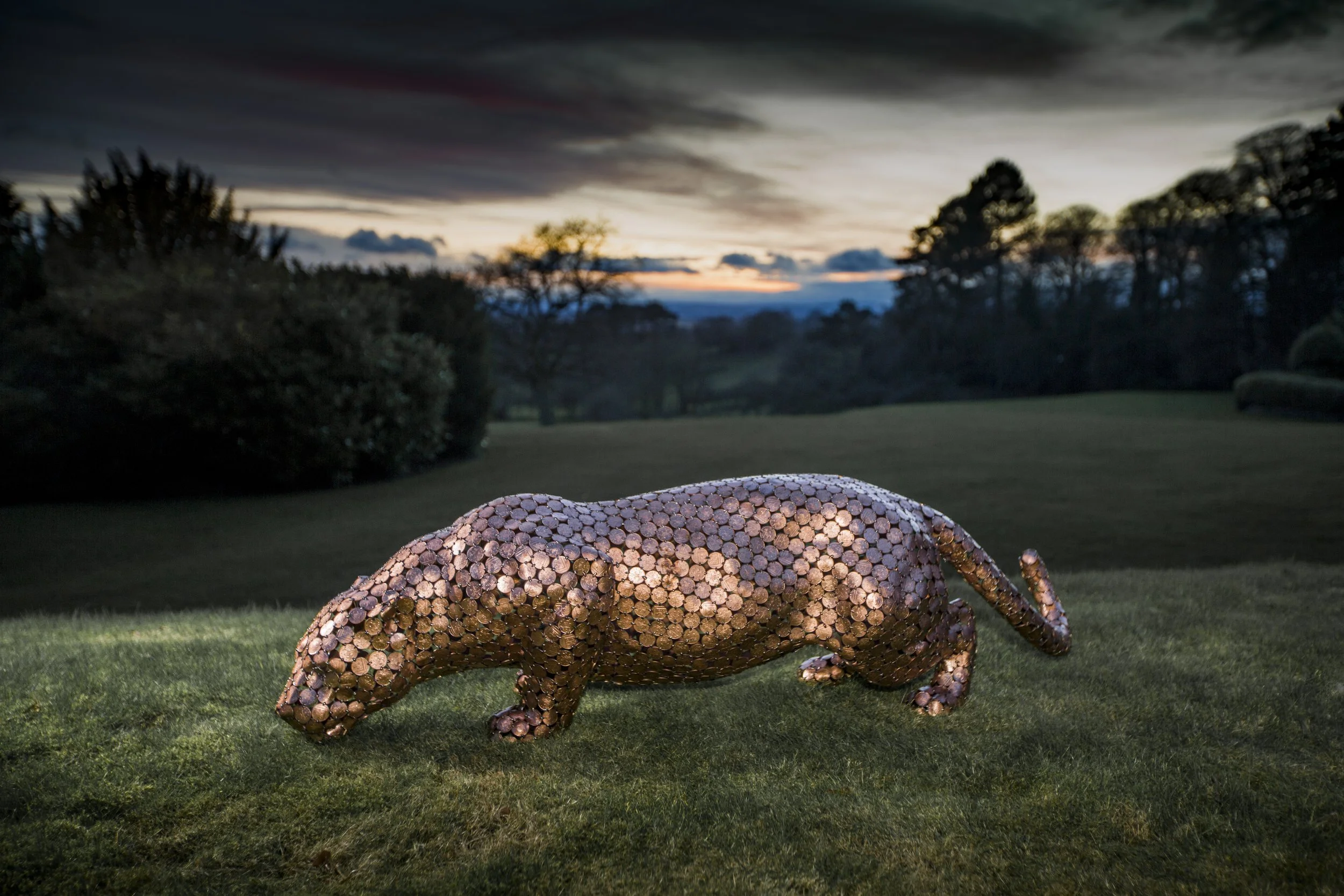 Life-size jaguar sculpture by Shaun Gagg, made from welded 2p coins. The shiny coins reflect light, highlighting the jaguar's powerful form and texture