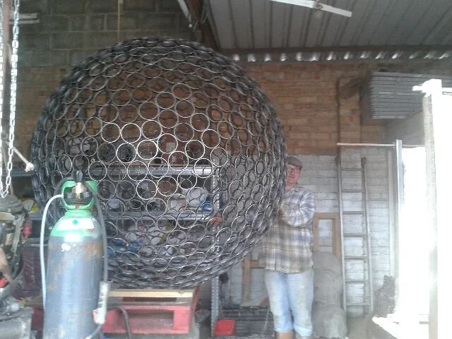 This sculpture is a sphere. Crafted by cutting steel pipes into slices and welding them together from the inside.  Note: The sphere will eventually rust over time.