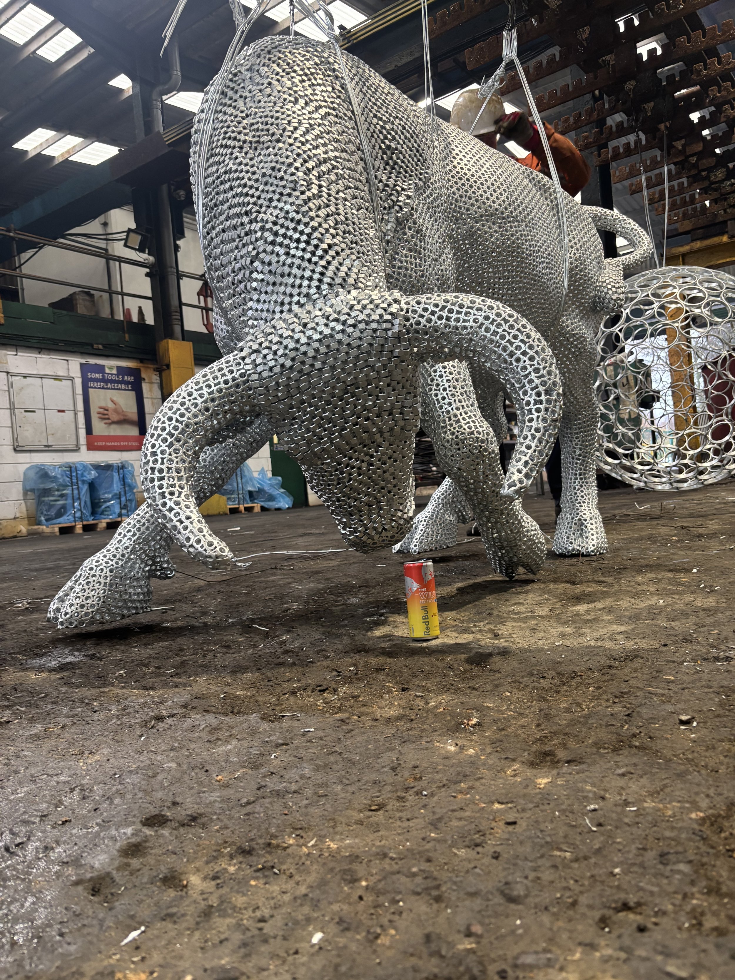 “A detailed bull sculpture by Shaun Gagg, built from 14,000 metal nuts and over 50,000 welds, giving it a strong, textured, industrial appearance.”
