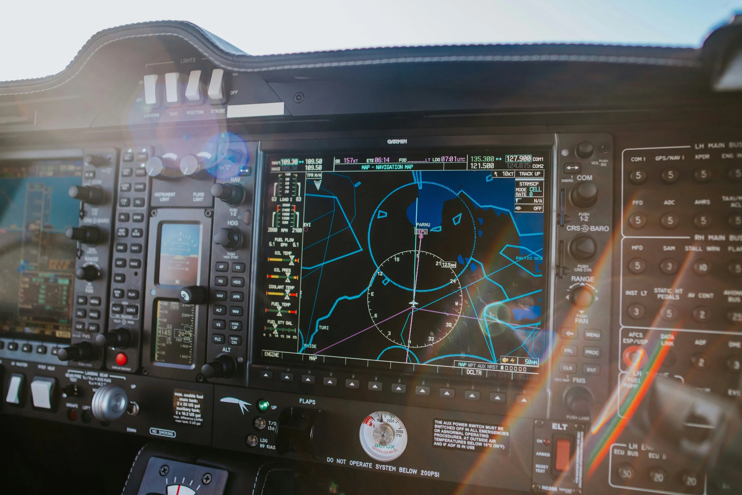 Interior view of an airplane cockpit with multiple control panels, screens, and navigation equipment.
