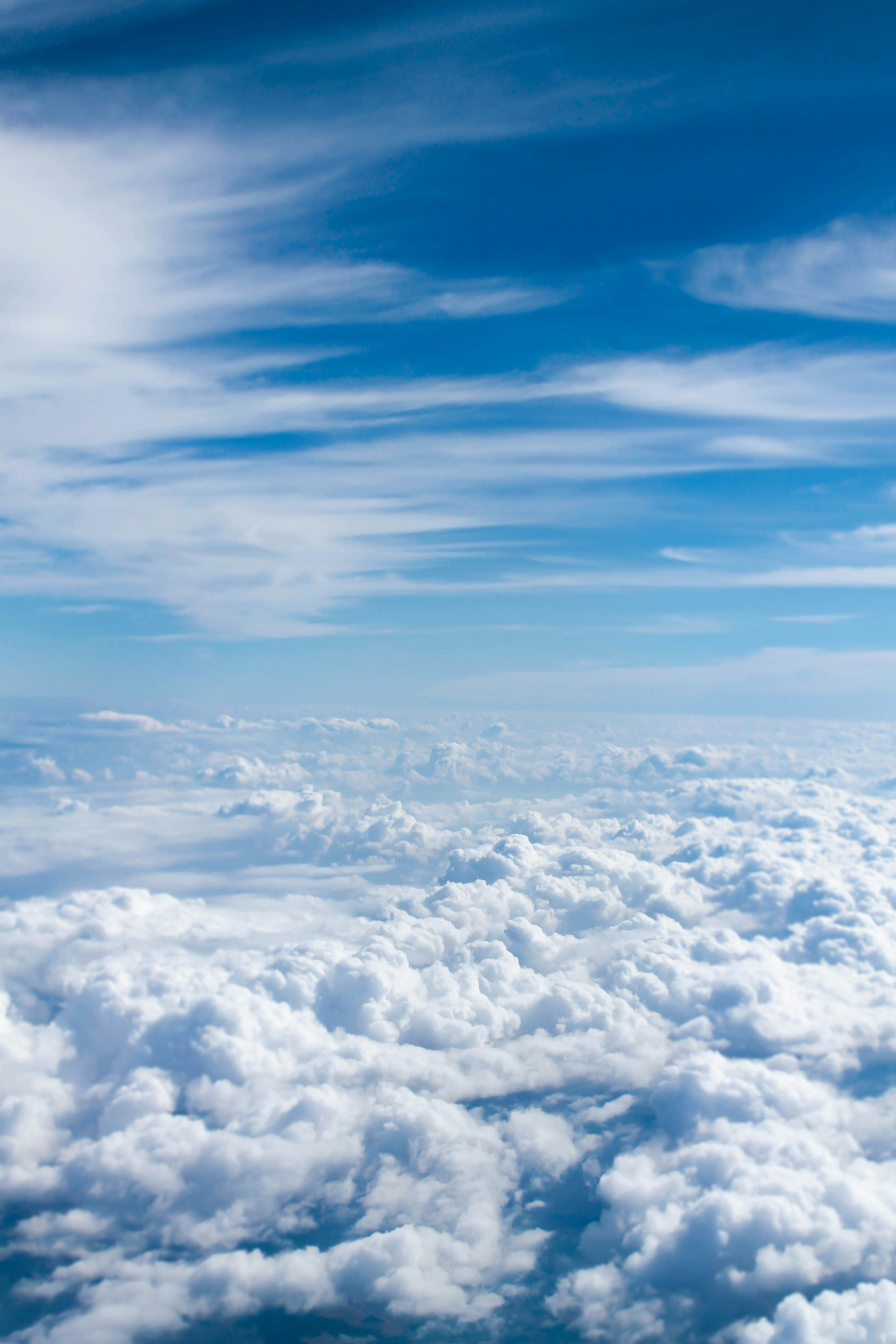 View of a blue sky with wispy clouds and fluffy white clouds below.