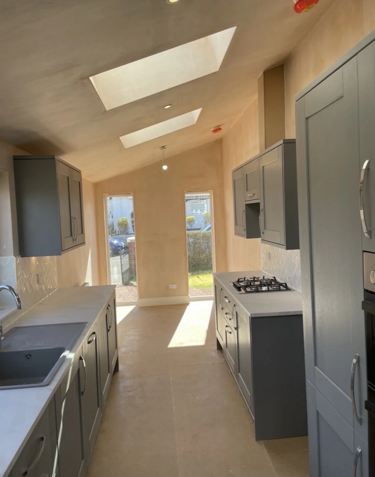 Kitchen with beige walls, blue cabinets, white countertops, a sink, a gas stove, and large windows.