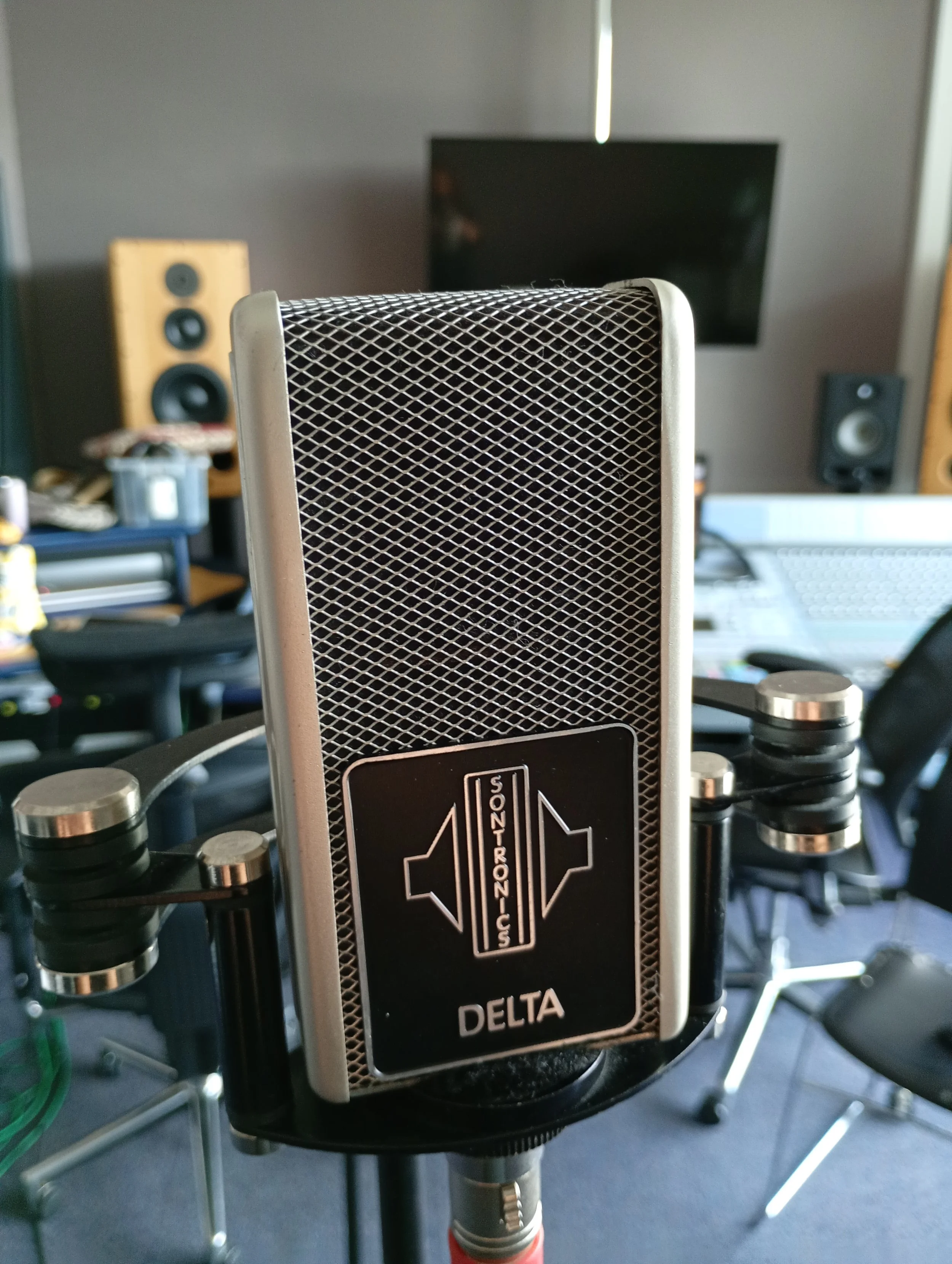 A close-up photograph of a Sontronics Delta ribbon microphone in a studio