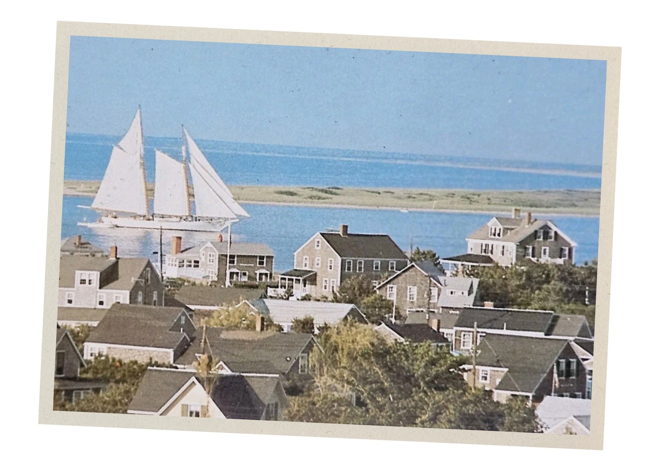 A photograph of a coastal town with houses and boats on the water, taken from an elevated perspective.