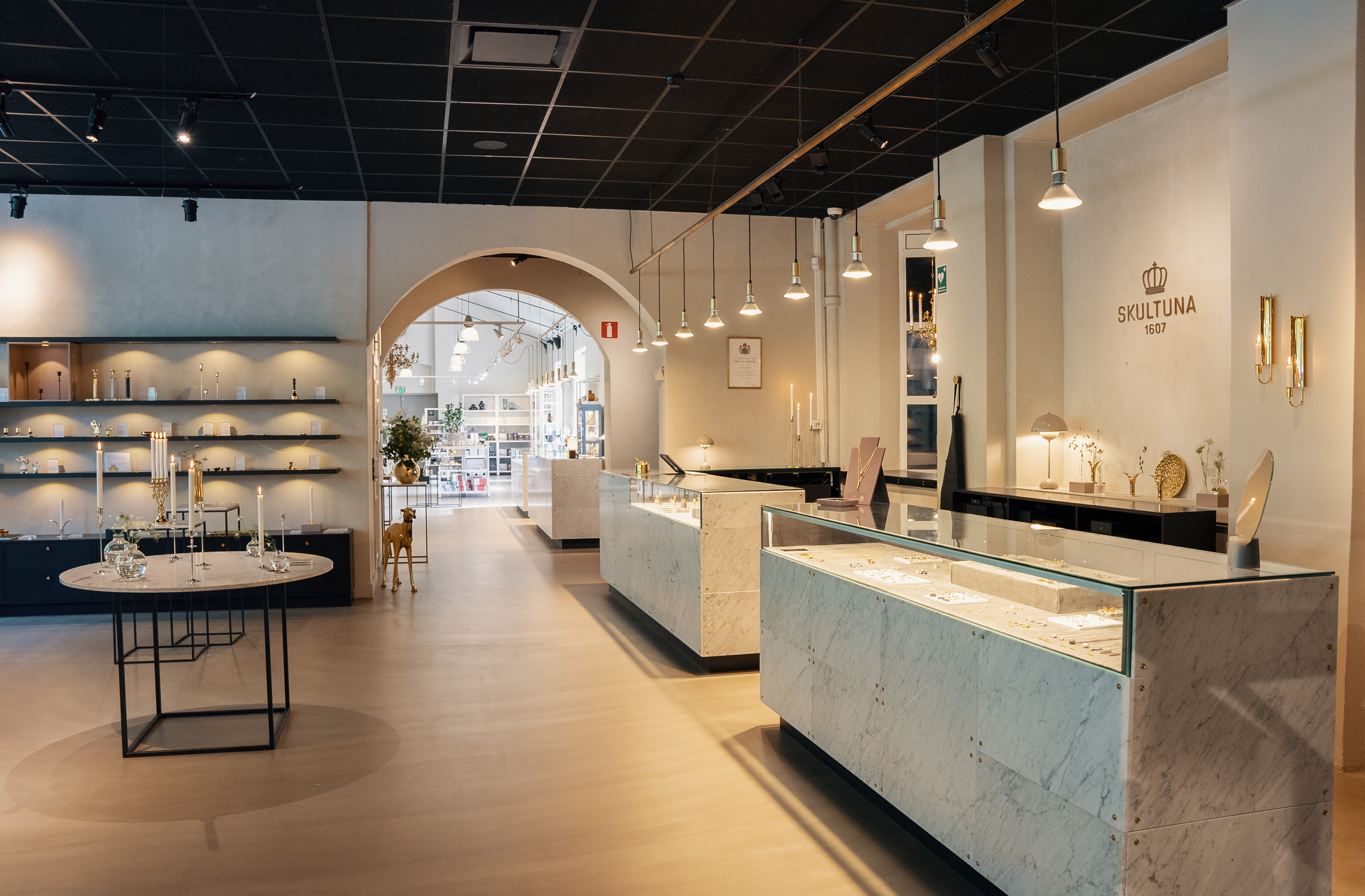 Inredningsbutik med glasdisplayer, hyllor och bord med ljus och dekorativa föremål.