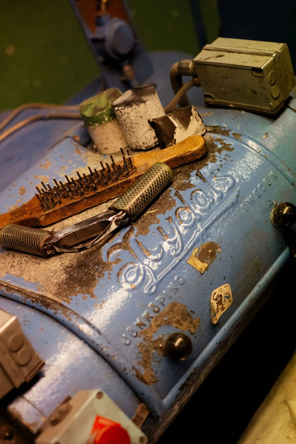 En gammal, rostig generator med verktyg och kablar på toppen.