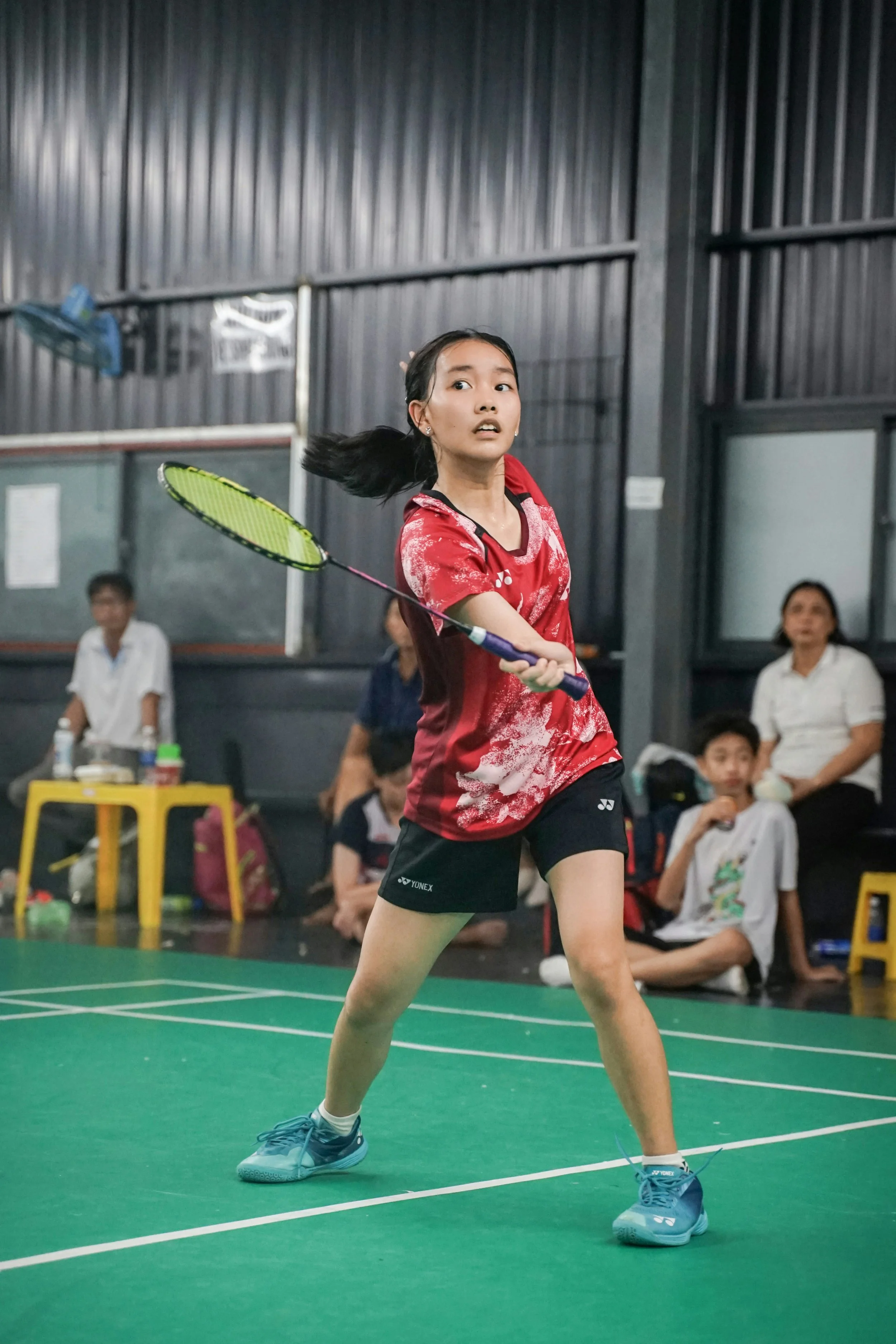 A young girl on a badminton court practicing badminton skills.