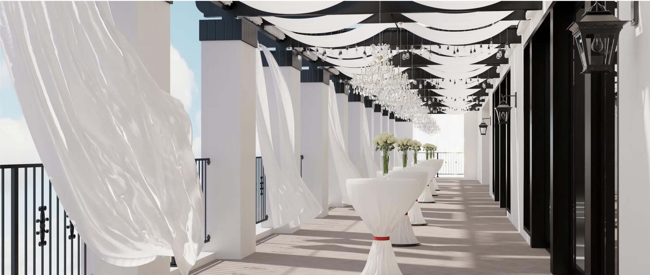 Elegant outdoor wedding reception with white draped tables, floral centerpieces, chandeliers, and black and white decor on a balcony with railings and lanterns.