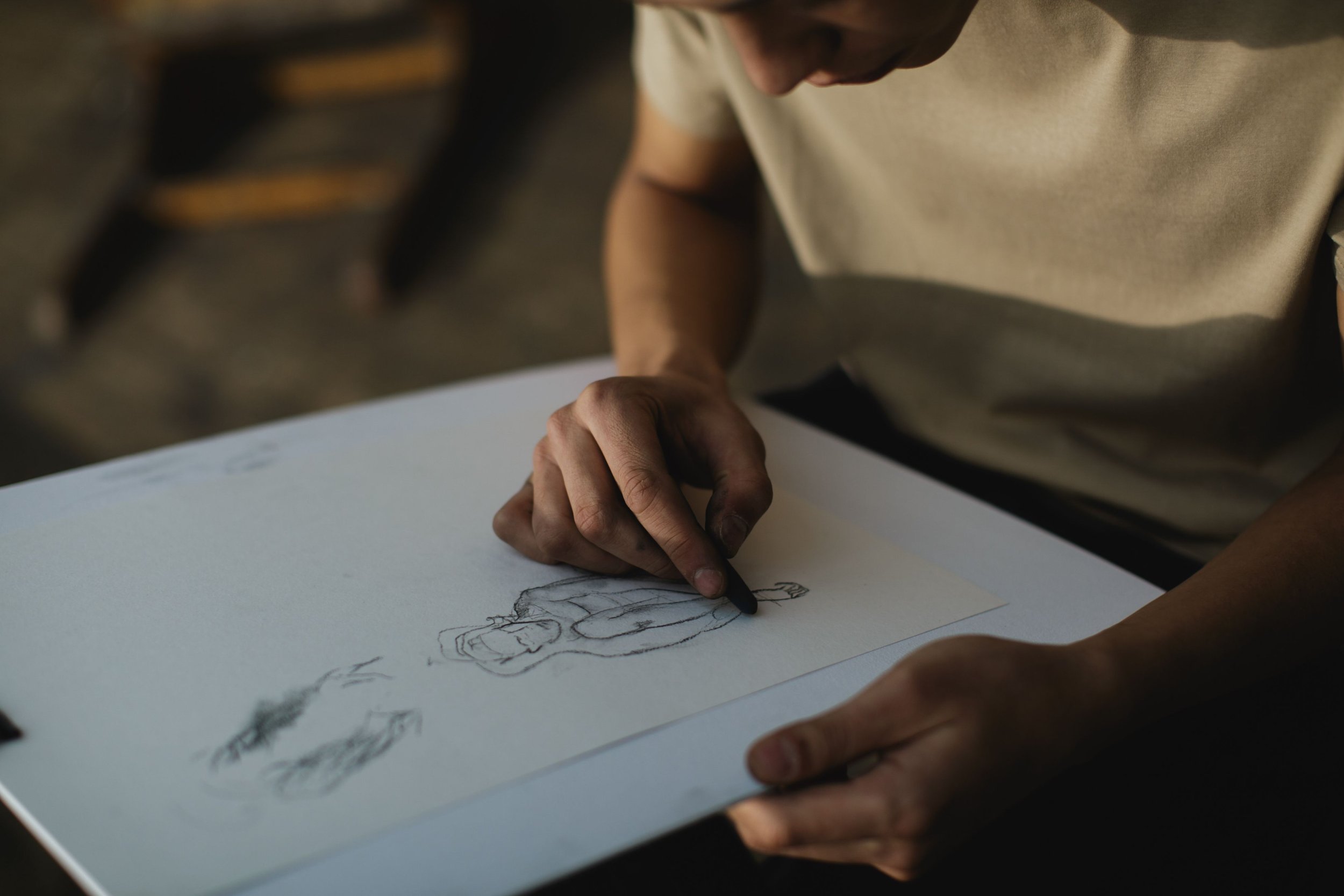 Person sketching a figure by hand on a large sheet of paper.