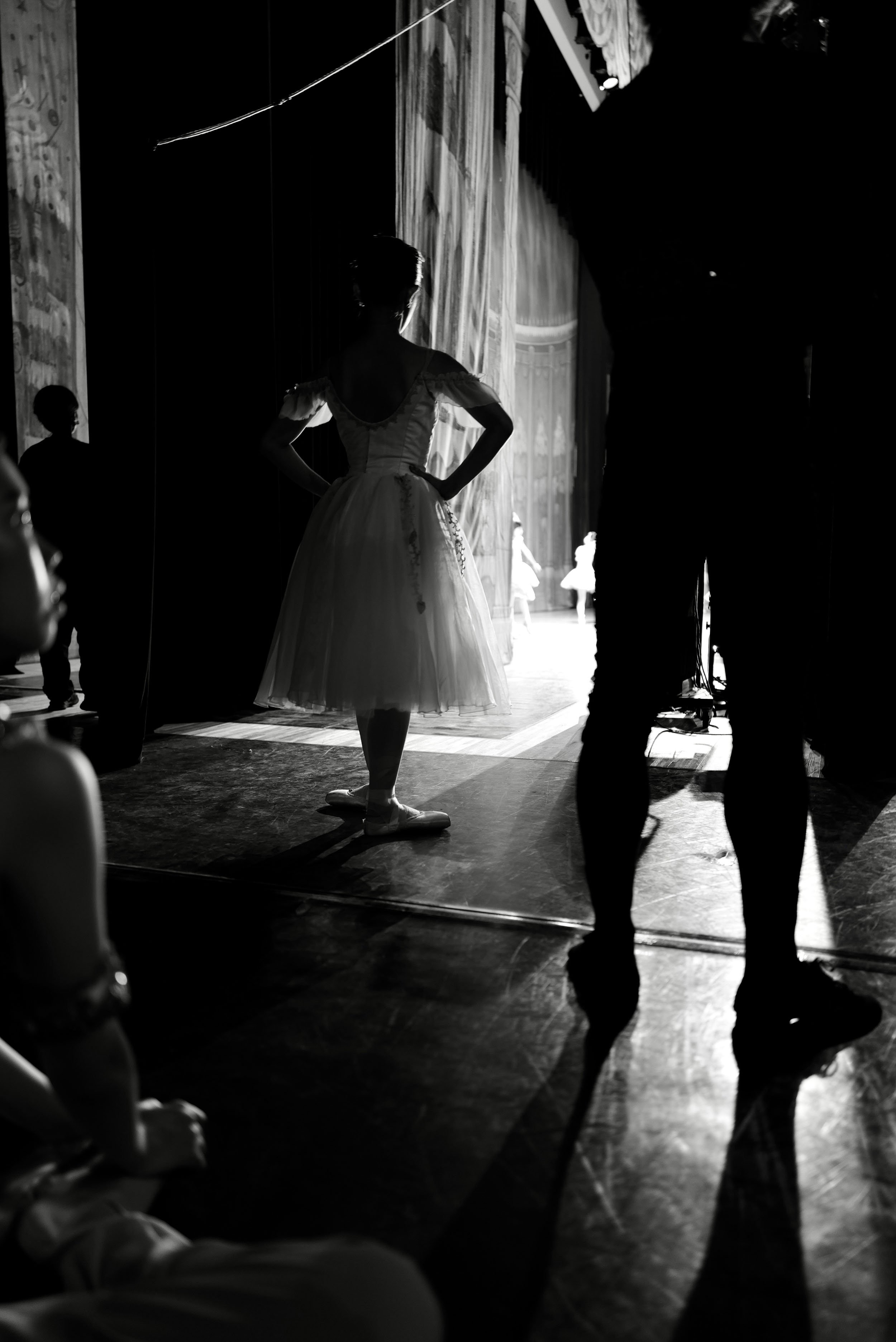 Black-and-white image of ballet dancers waiting in the wings before going onstage.