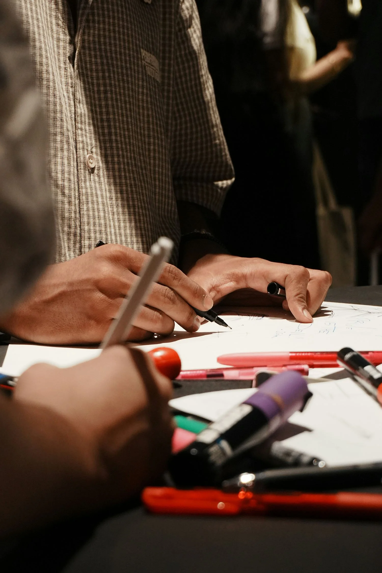 People collaborating around a table with markers and creative materials.
