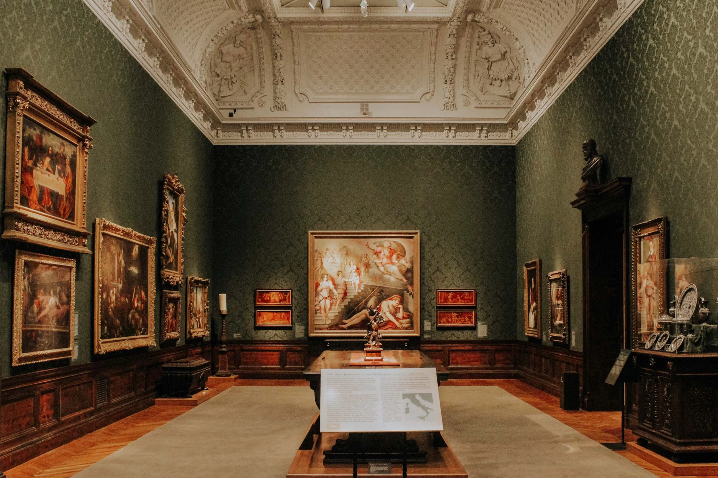 Historic art museum gallery with framed paintings and ornate architectural details.