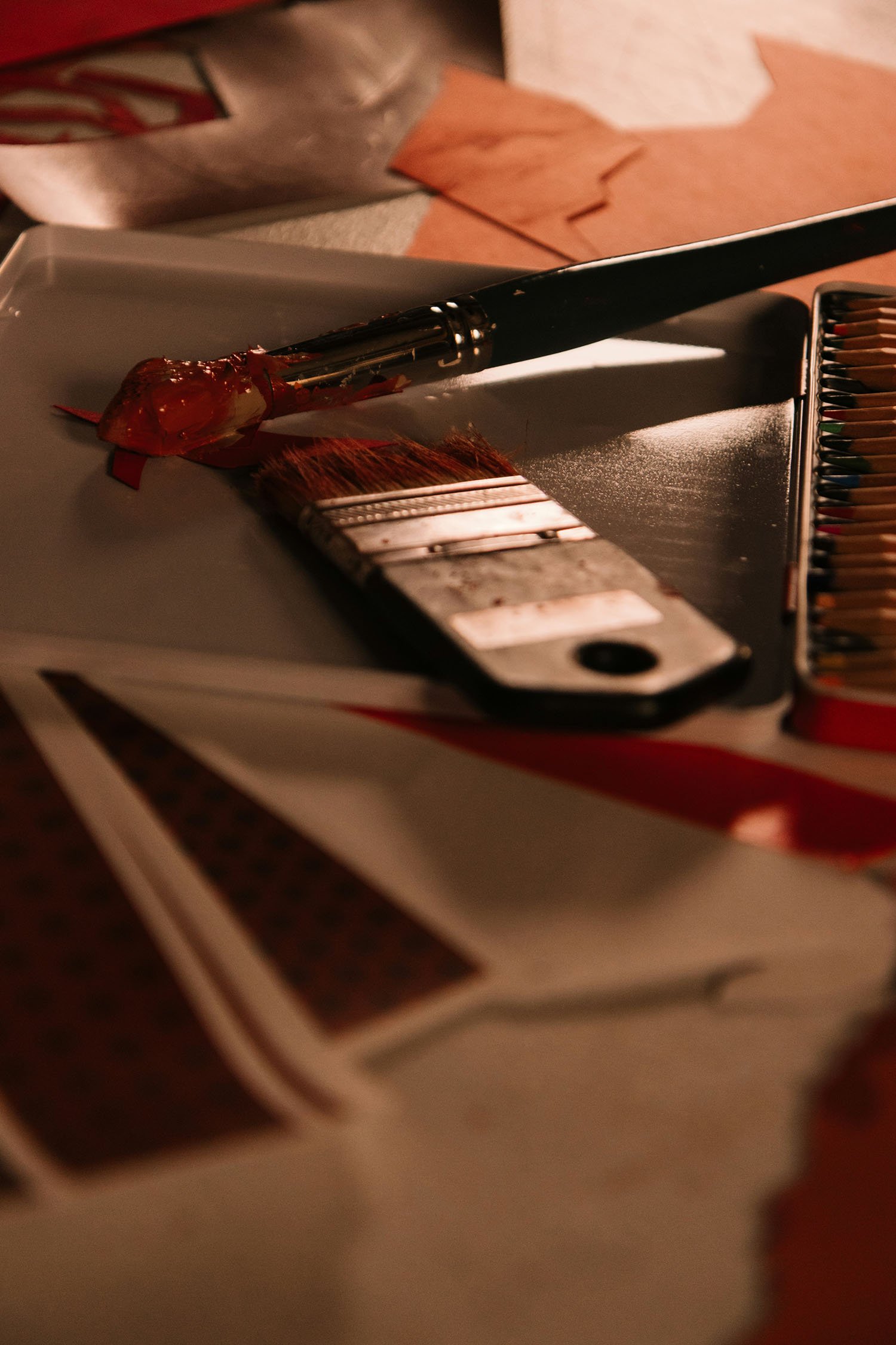 Paintbrushes, colored pencils, paper, and other art-making materials on a table.
