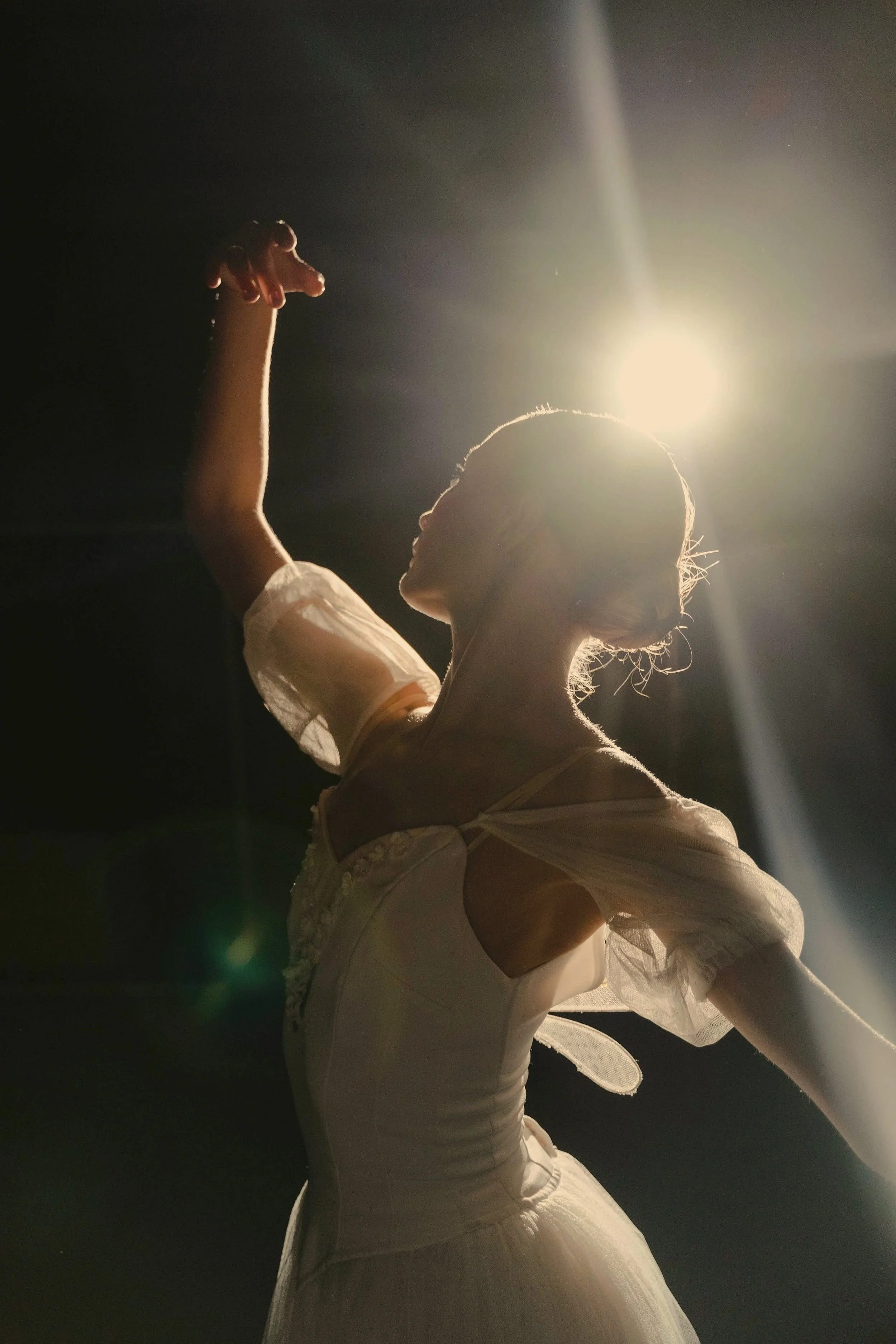 Ballet dancer performing onstage under a bright spotlight.
