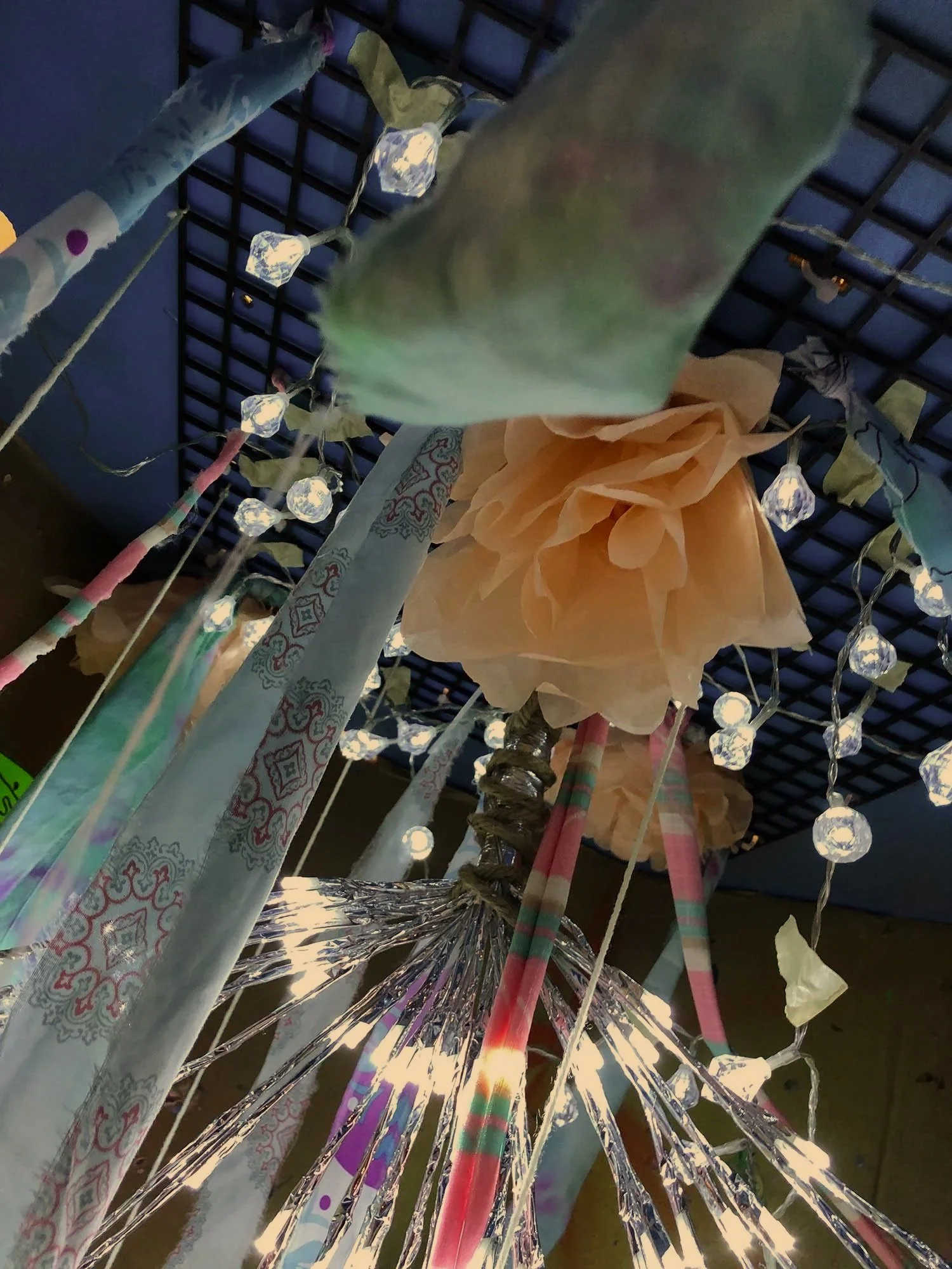 “JOY ReDefined” artwork featuring a colorful mixed-media installation with hanging lights and fabric.