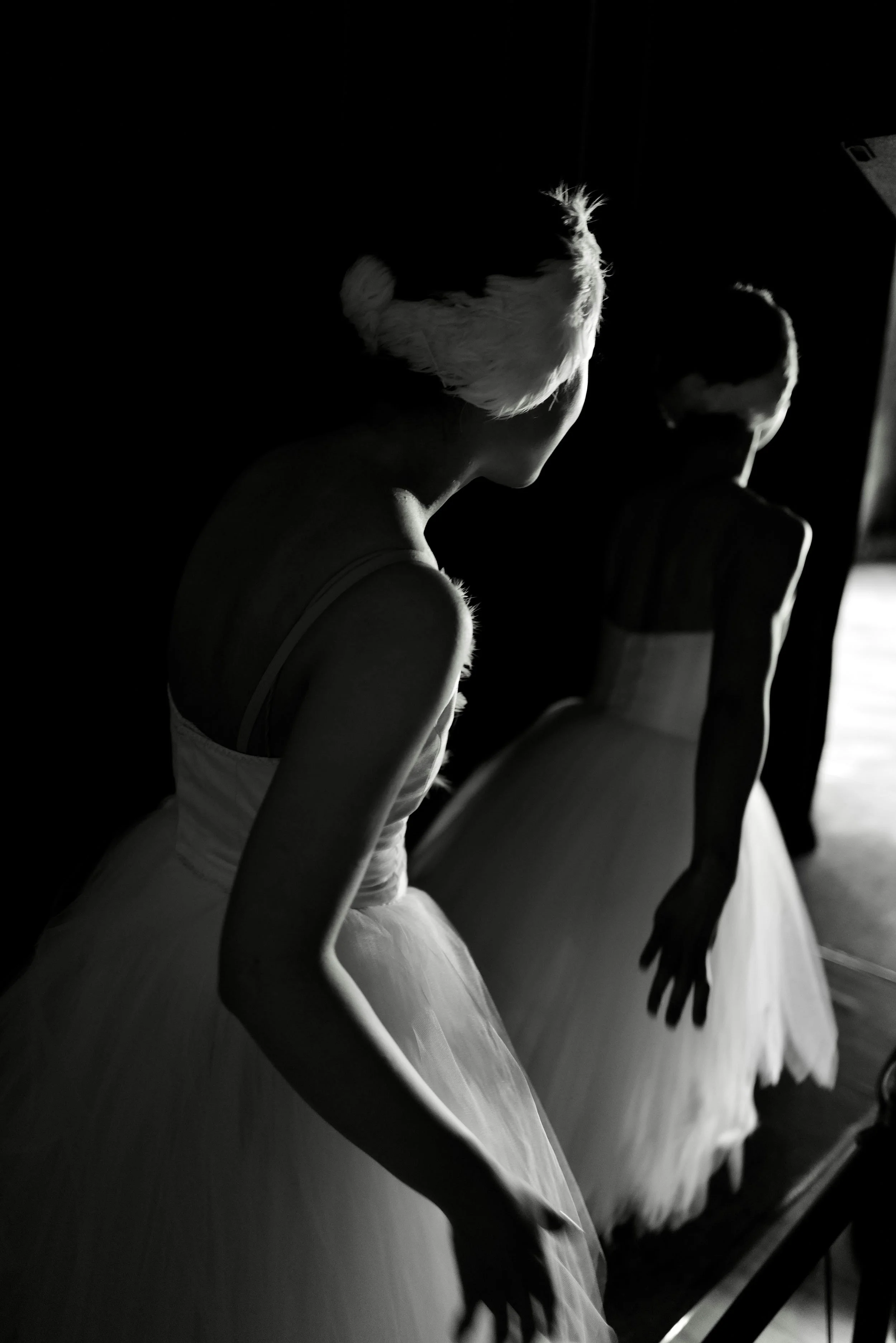 Black-and-white image of ballet dancers waiting backstage in costume.