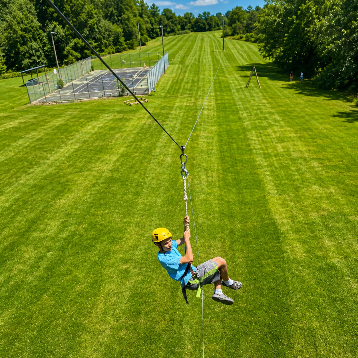Child ziplining over a grassy field on a sunny day.