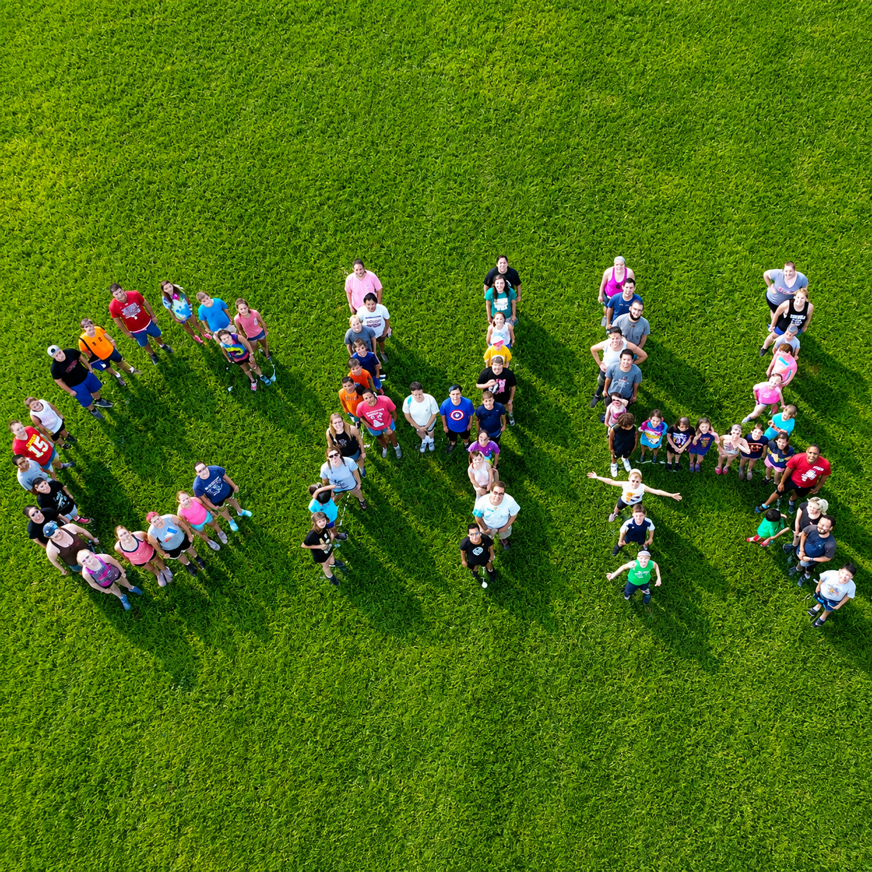Aerial view of a large group of people forming the word 'GIRL' on a lush green field.