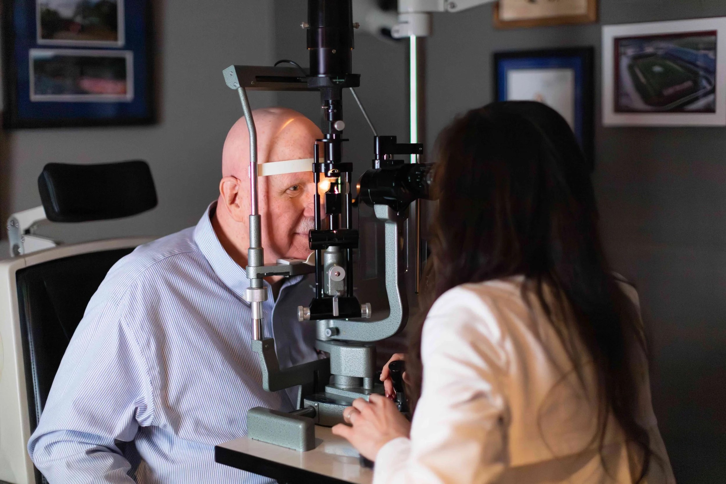 A doctor performs an eye exam on a patient using a slit lamp in a medical clinic.
