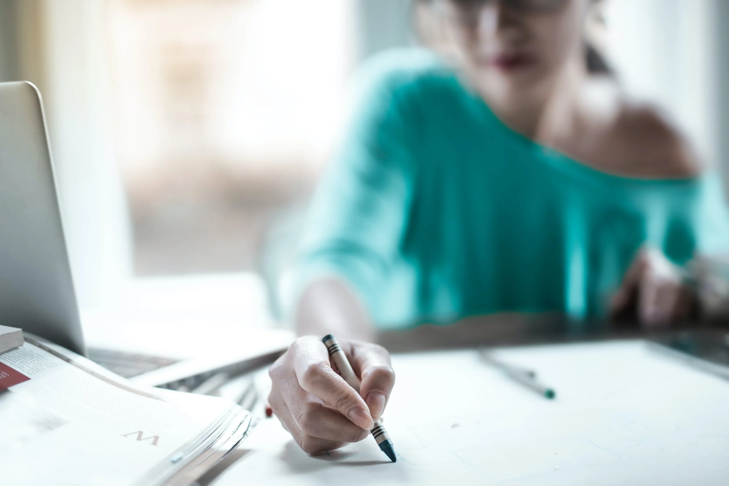 Woman participating in an expressive art therapy session using crayon paper and her laptop.