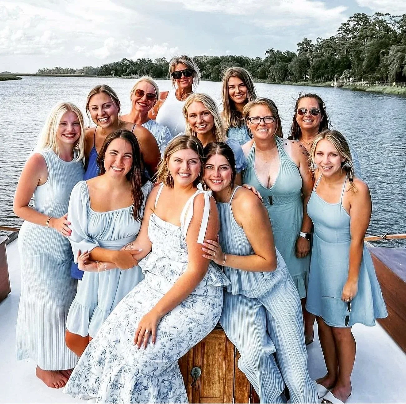 Group of women in light blue dresses posing on the bow of the yacht