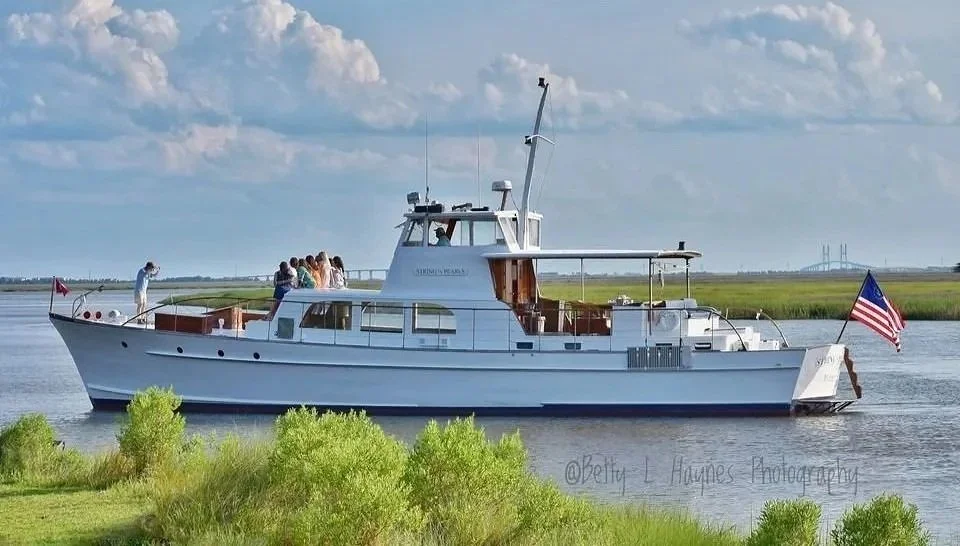 String of Pearls yacht cruising past marsh grass, flying an American flag