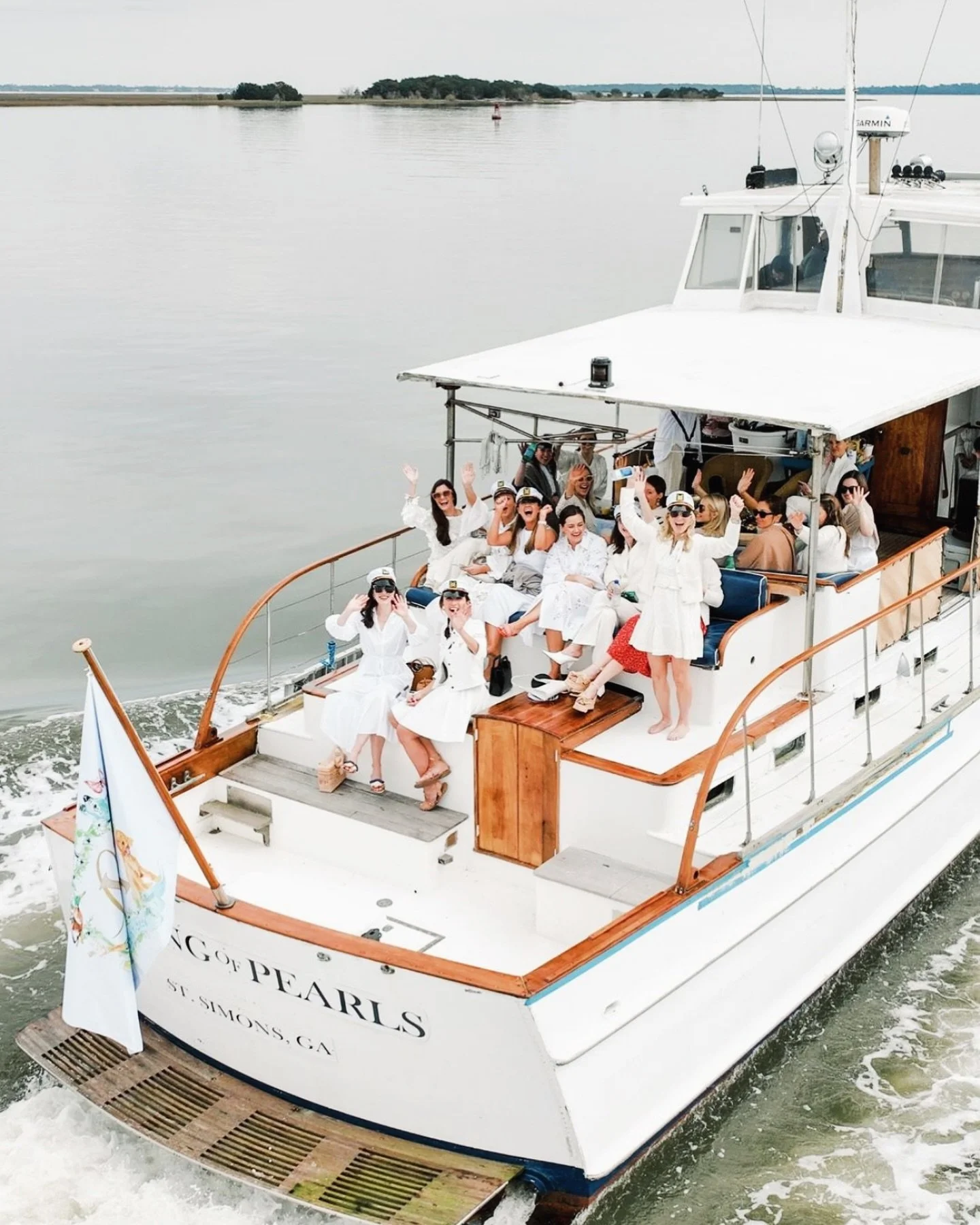 String of Pearls yacht underway with guests dressed in white on the aft deck