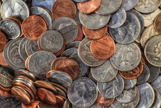 A pile of mixed U.S. coins including pennies, nickels, dimes, and quarters.