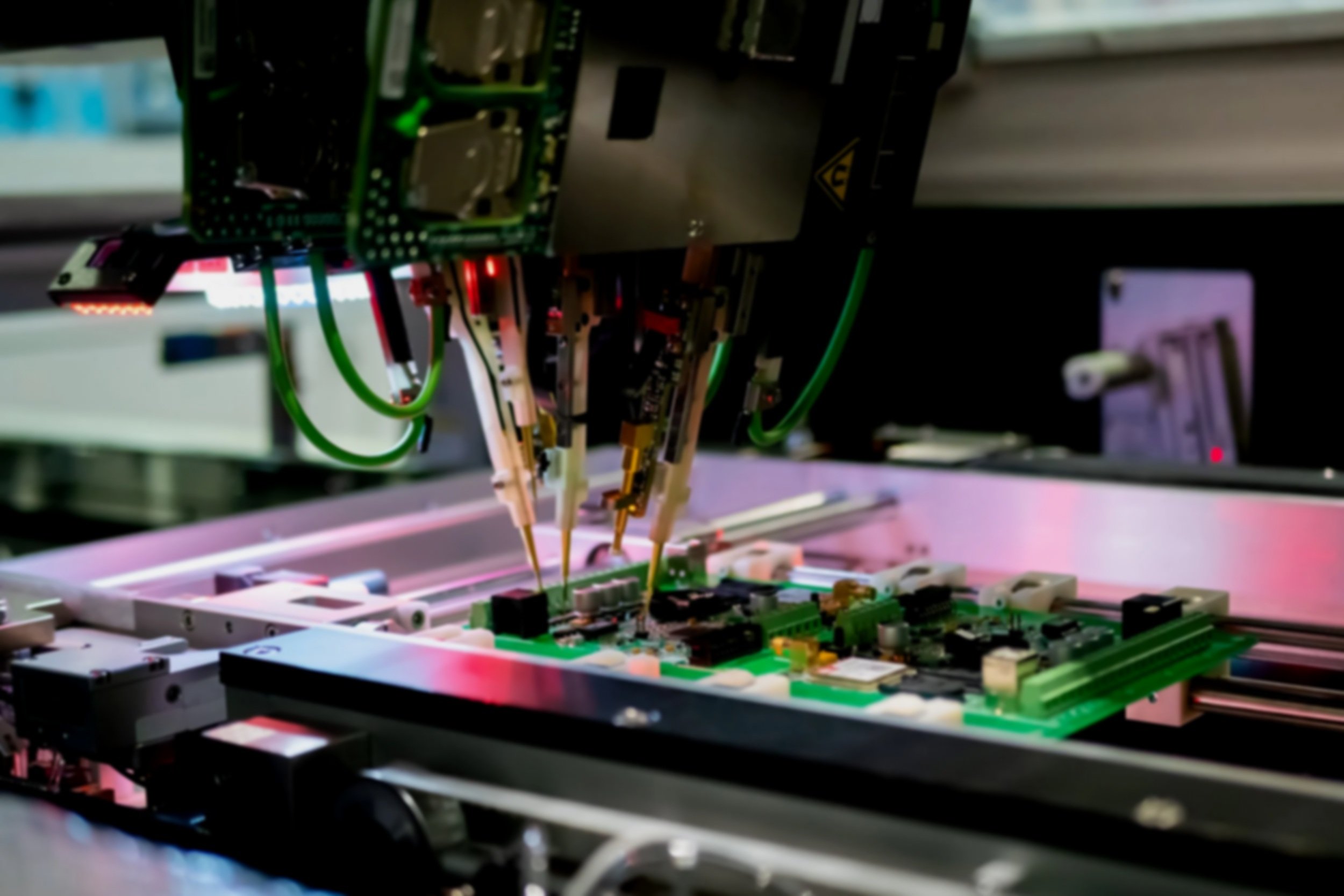 Close-up of a scientific or medical device with circuit boards, wires, and electronic components, illuminated by green and red lights.