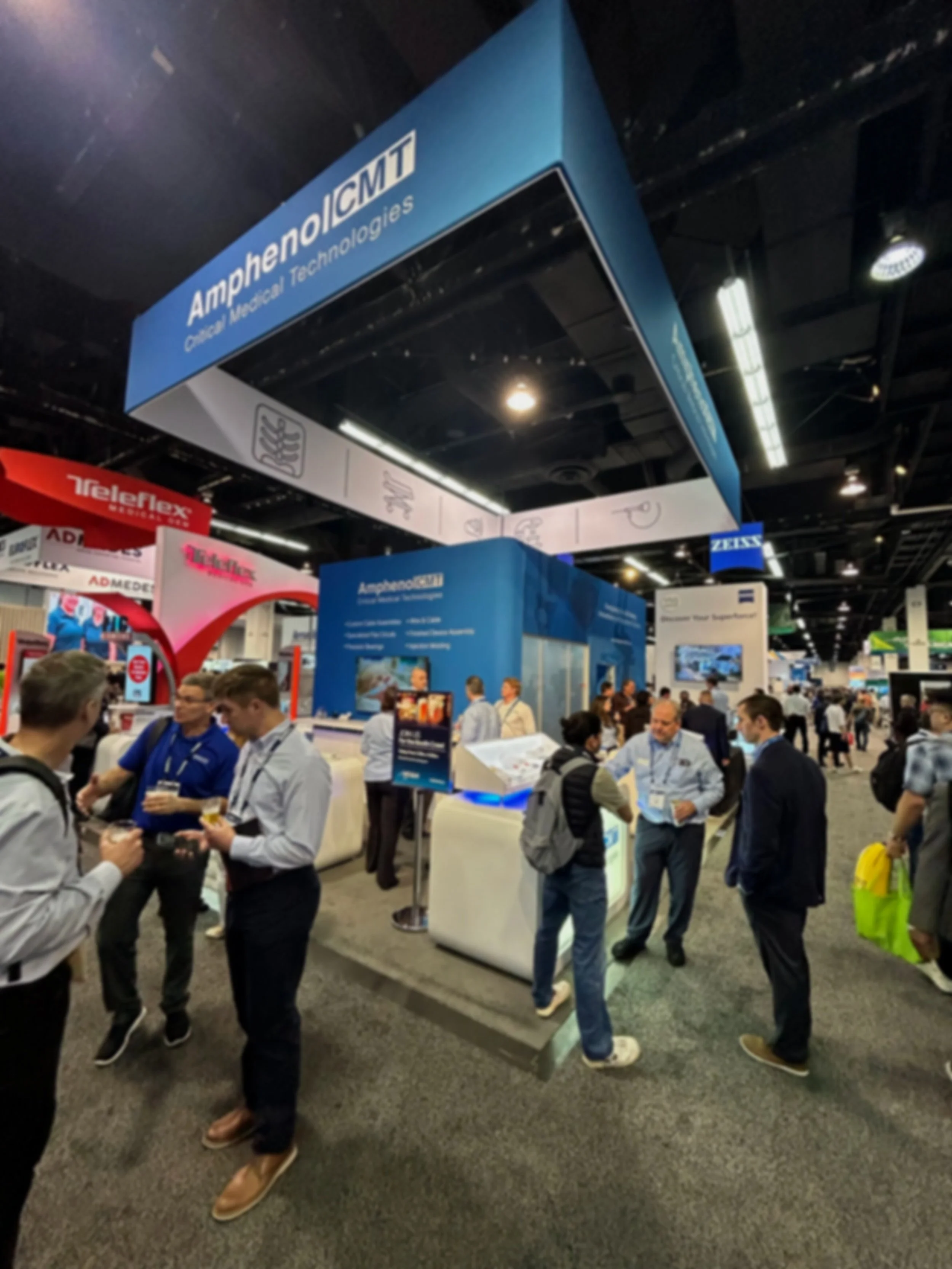 People gathered at an exhibition booth for Amphenol ICT at a trade show.