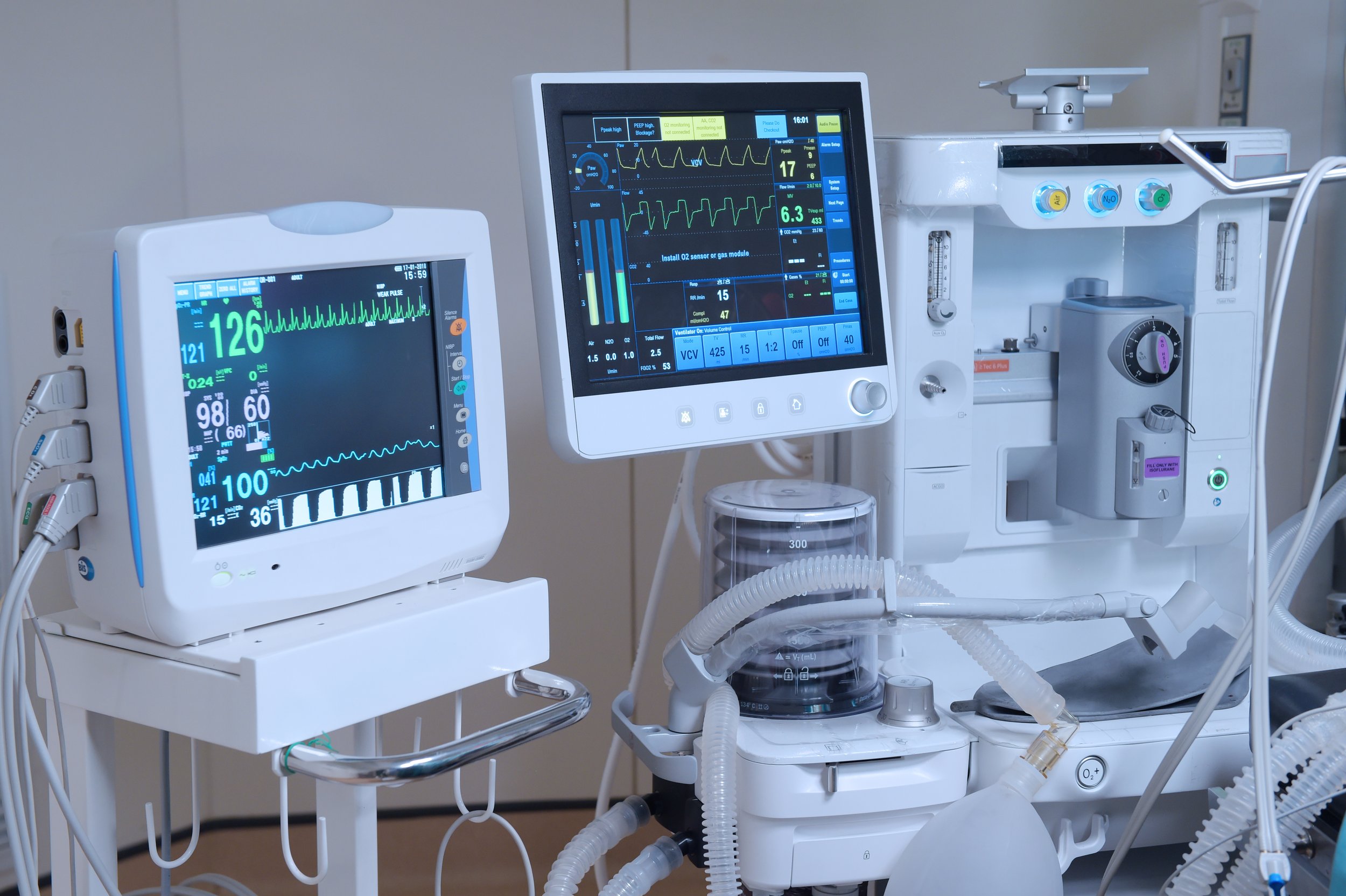 Medical monitors and equipment in a hospital setting, including vital signs monitors displaying heart rate and other vital information.